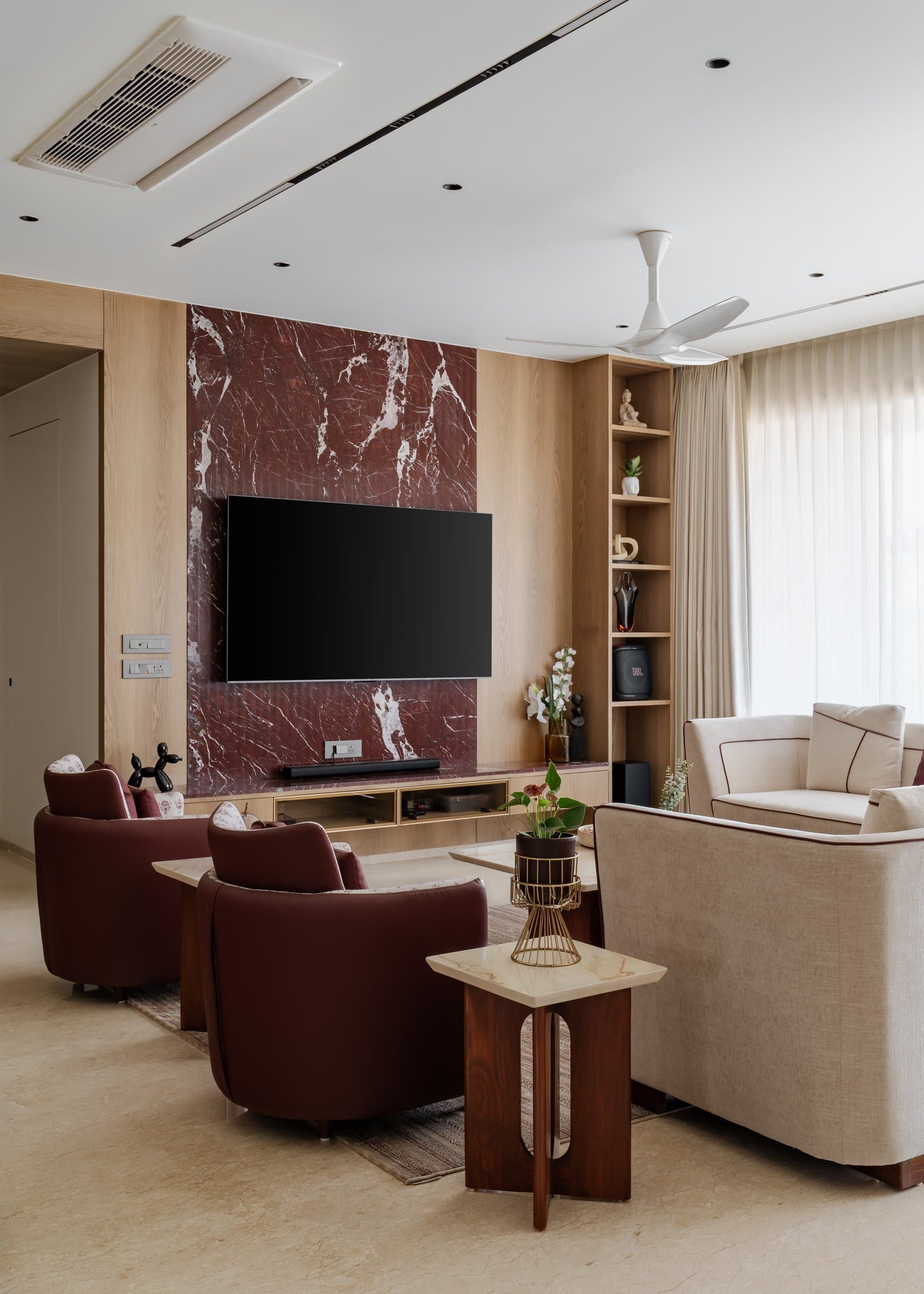 The seating group, where oxblood leather armchairs converse with an ivory linen sofa piped in the same deep red