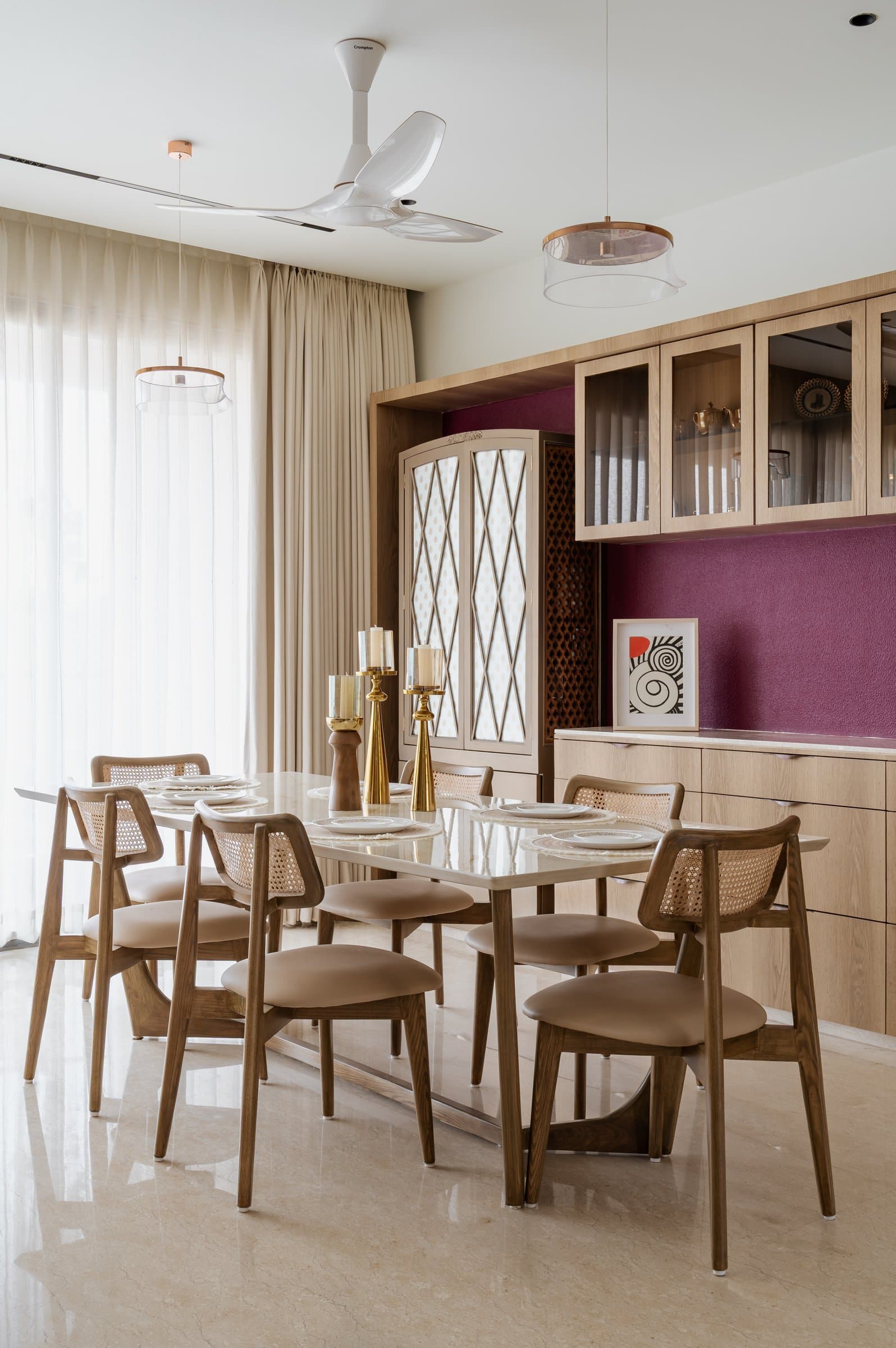 The dining area, where cane-back chairs and a stone-topped table sit before an aubergine accent wall
