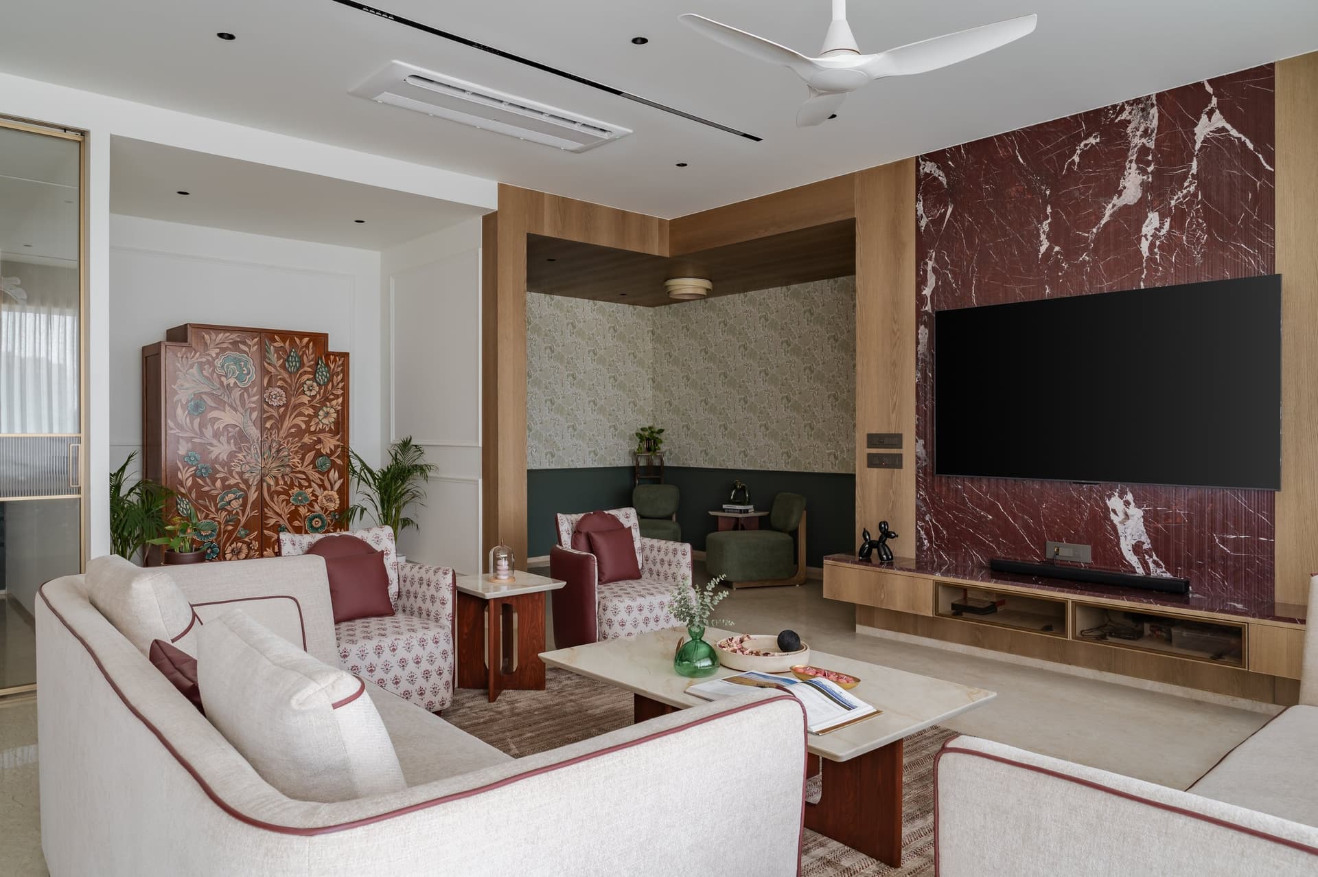 The secondary lounge, where a hand-painted heirloom cabinet anchors the room against a sage-papered nook