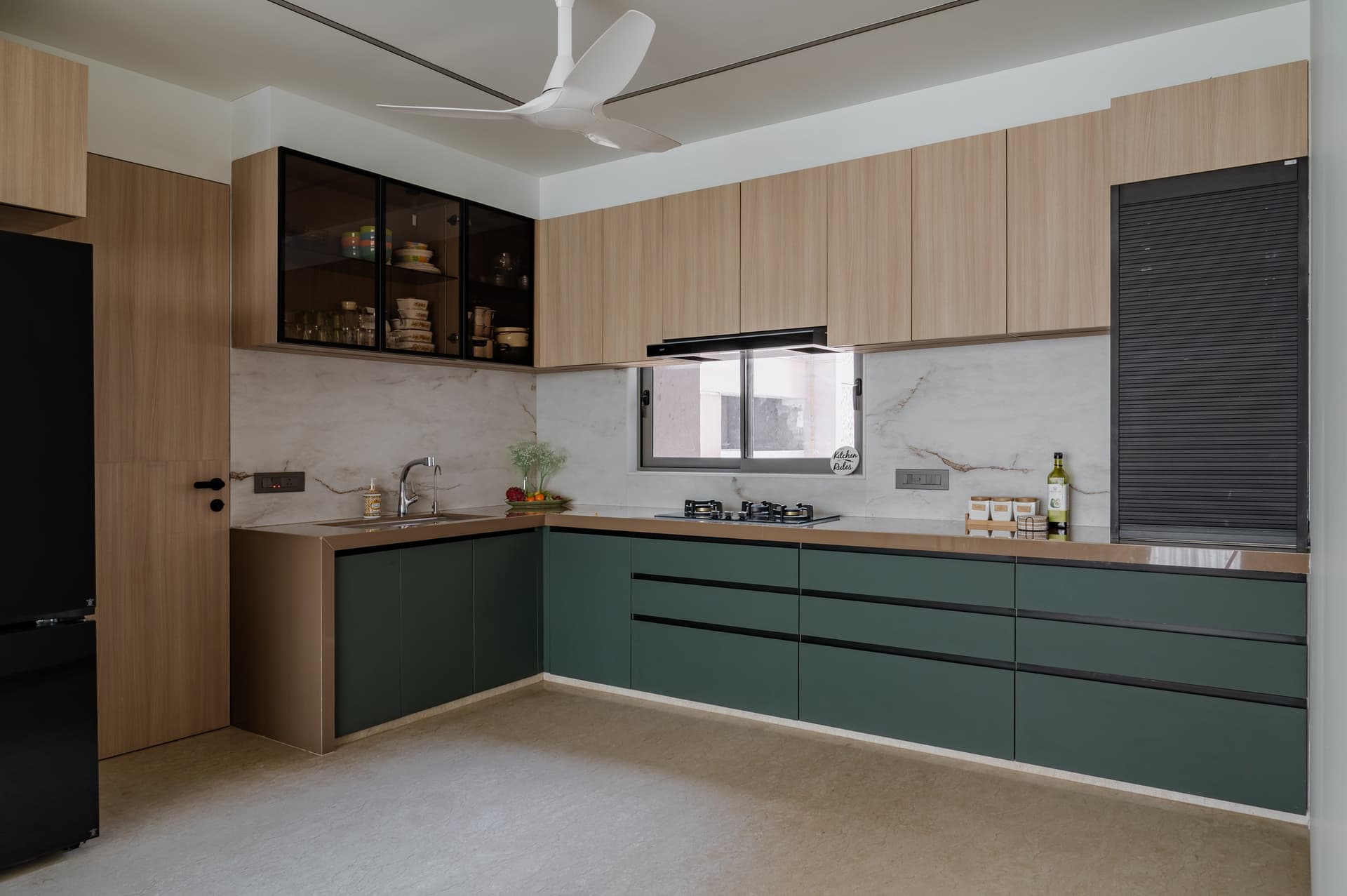 The kitchen, where deep forest-green cabinetry pairs with warm oak uppers and a book-matched stone backsplash