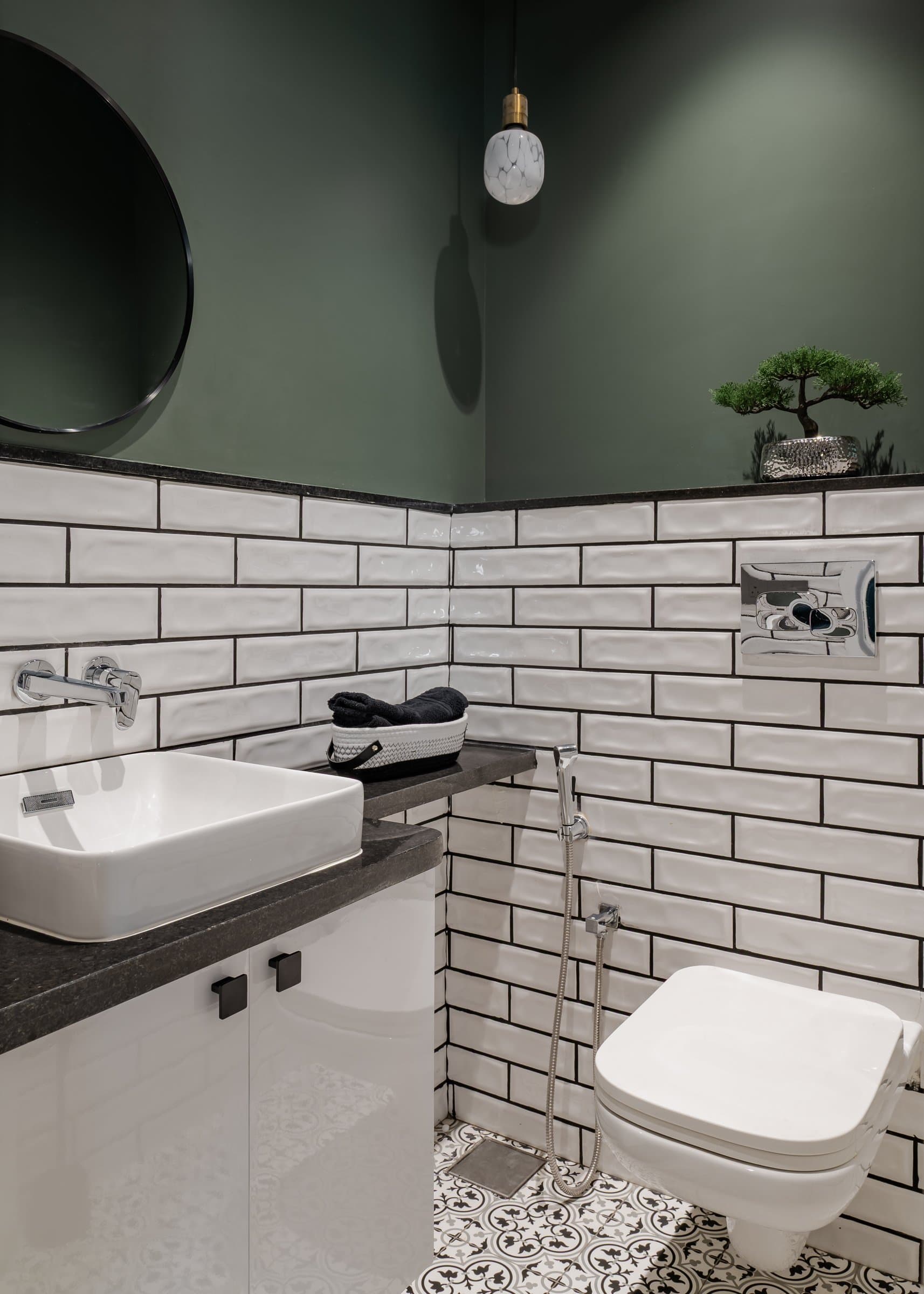 The powder room, where beveled subway tiles meet a deep forest-green upper wall and patterned monochrome floor
