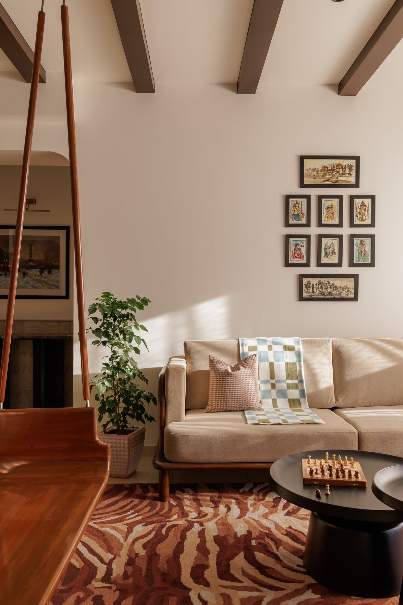 In the living room, a curated wall of miniatures anchors the neutral sofa, celebrating heritage without overwhelming the architecture