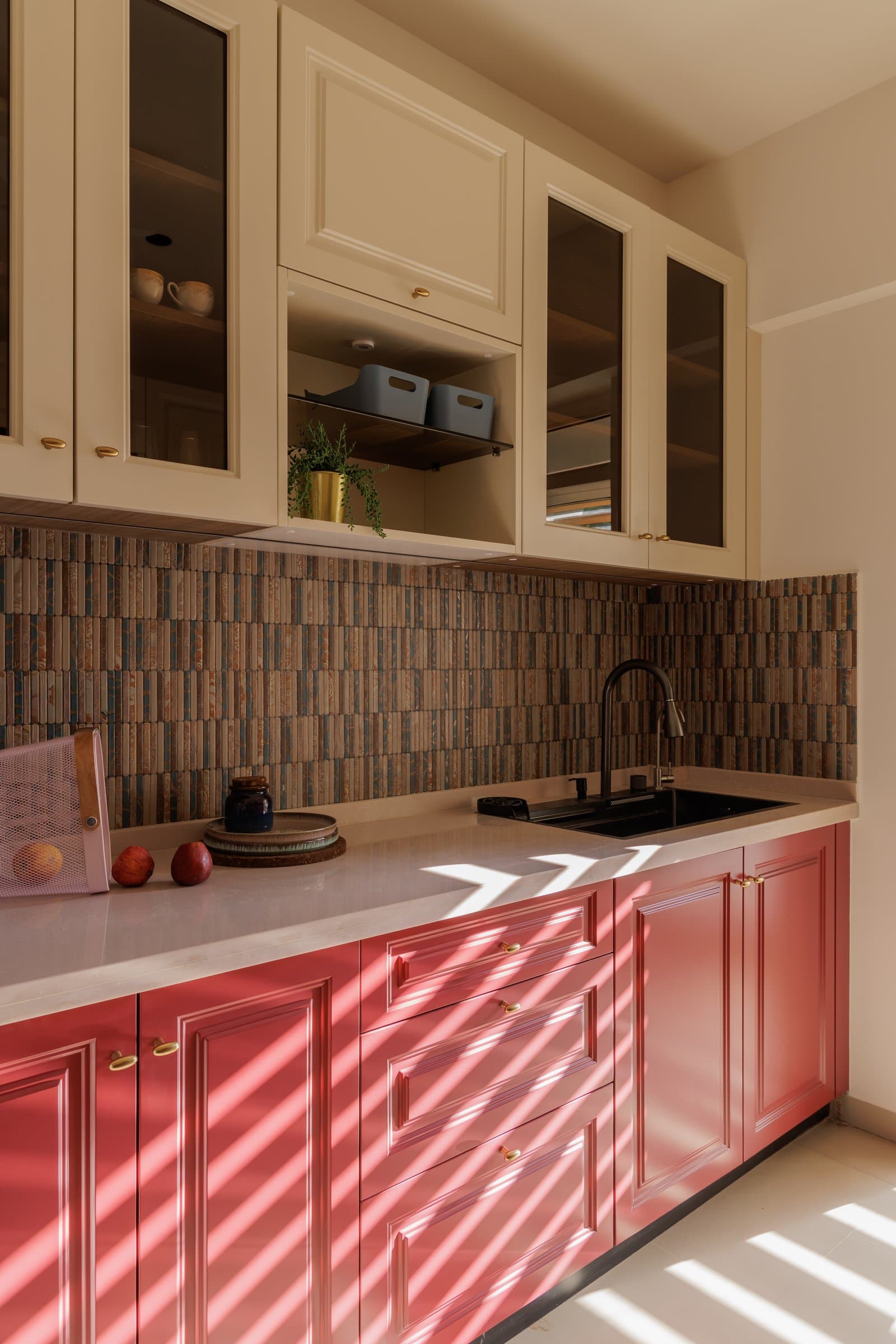 The kitchen, where coral panelled cabinetry and an earthen mosaic backsplash bring the home's most saturated colour moment