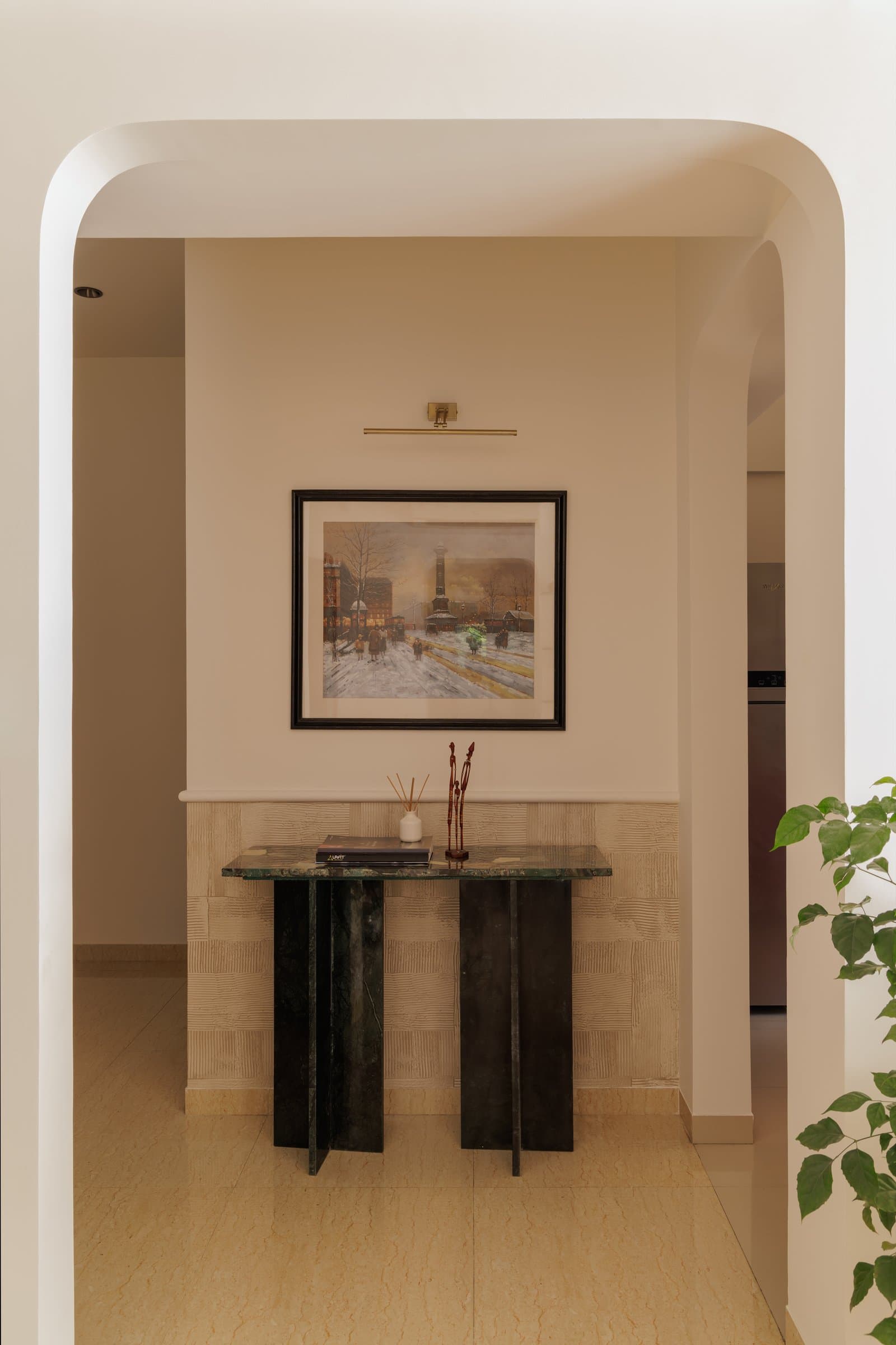 The entry, where a green stone console and softly arched opening set the tone for the home's material and cultural register