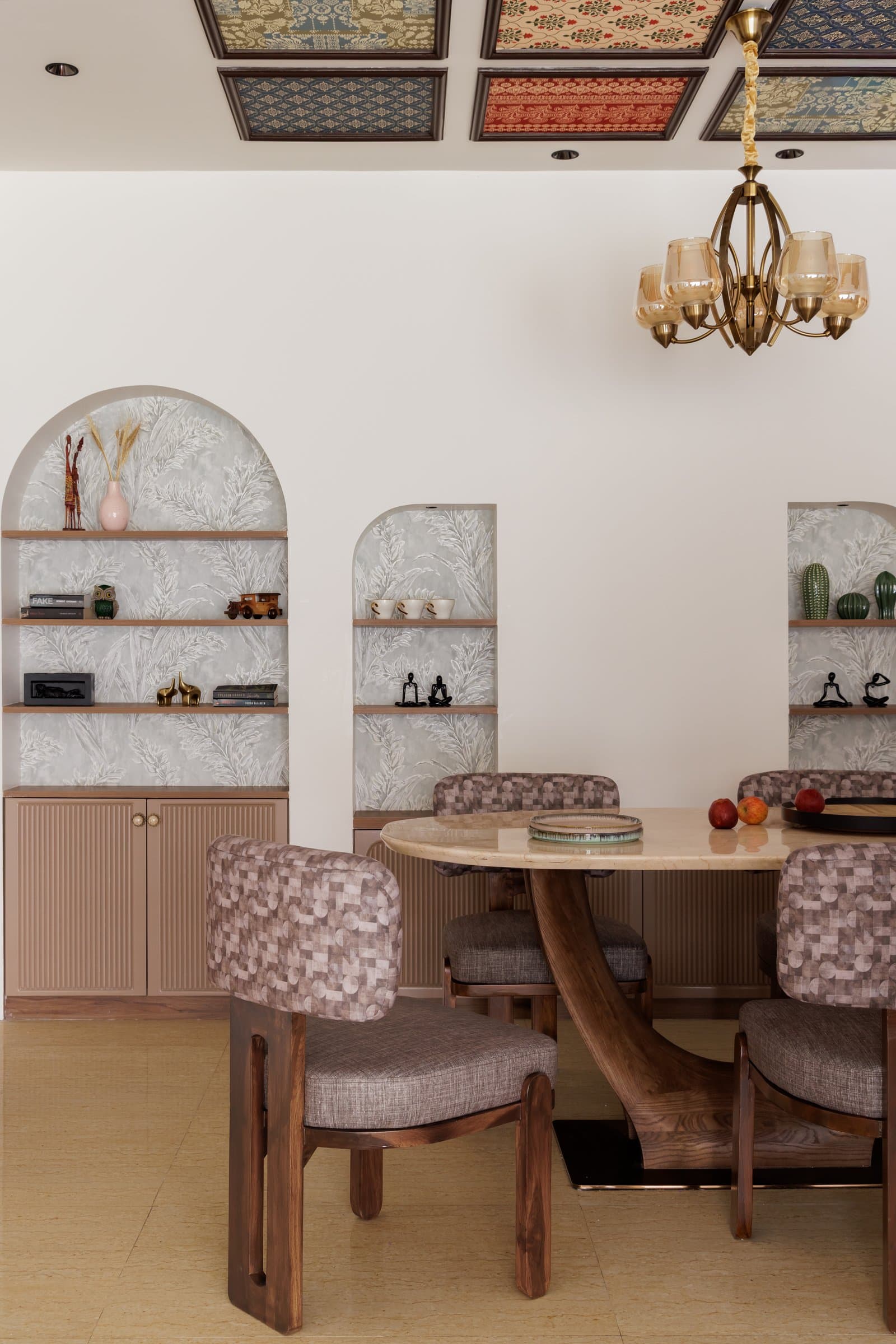 The dining table, an oval stone top on a sculptural wooden base, set against arched niches lined in botanical-print wallpaper