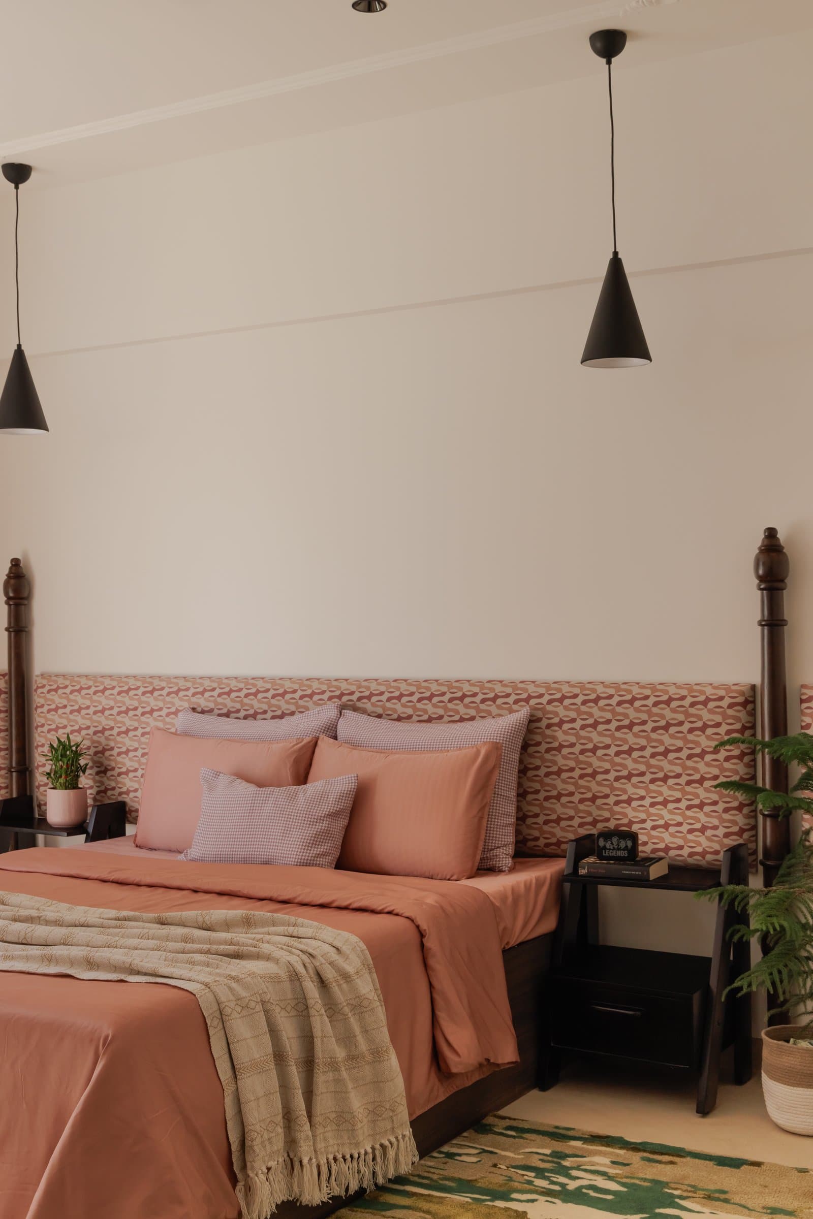 The second bedroom bed, layered with coral sheeting and a woven throw, its turned posts introducing a traditional silhouette