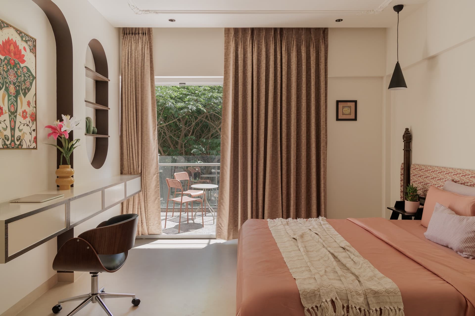 The second bedroom, where coral bedding, turned wooden posts, and a balcony opening balance rest, work, and pause