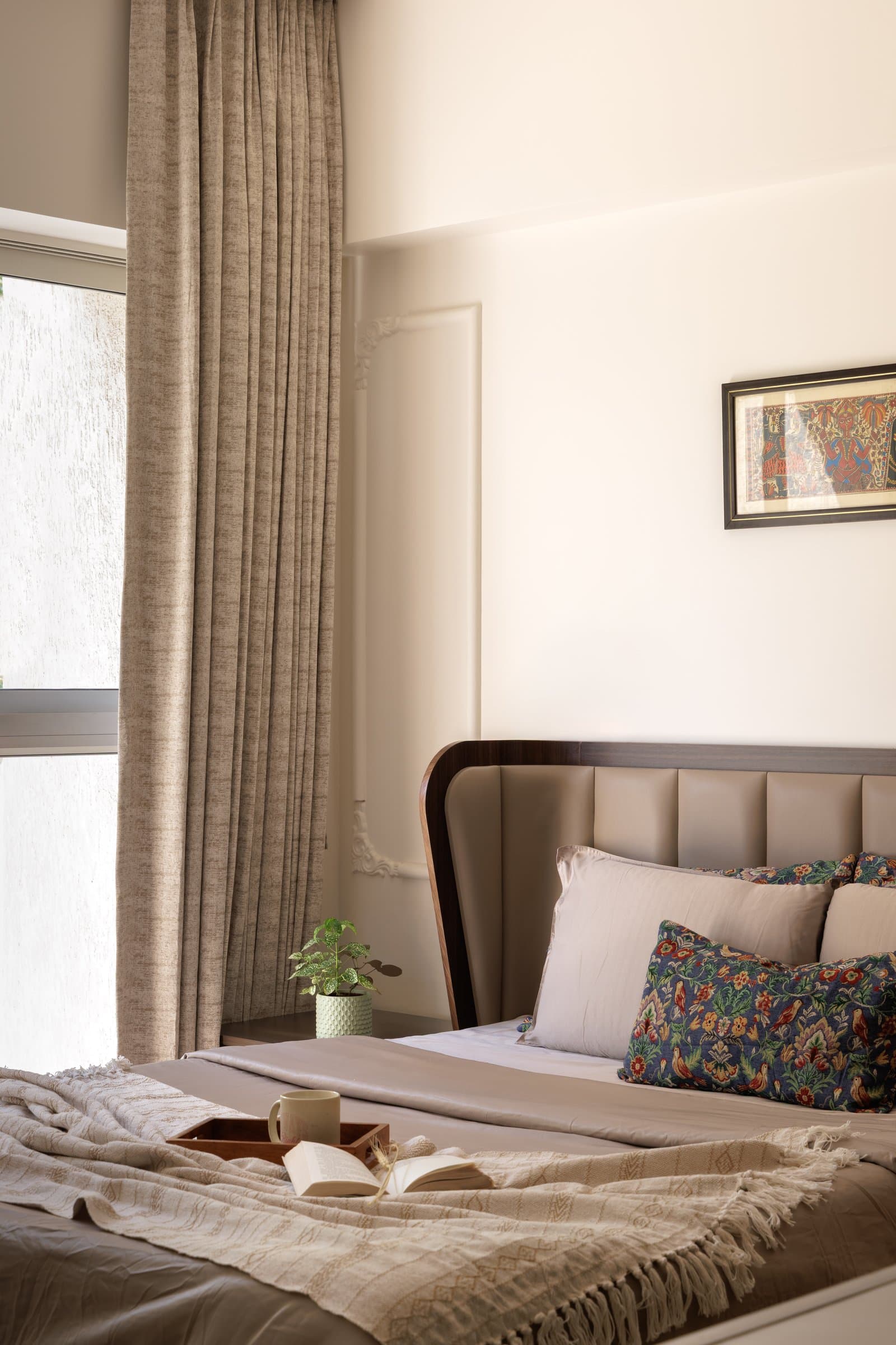The master bedroom, where a channelled headboard and folk-inspired artwork keep the palette quiet and grounded
