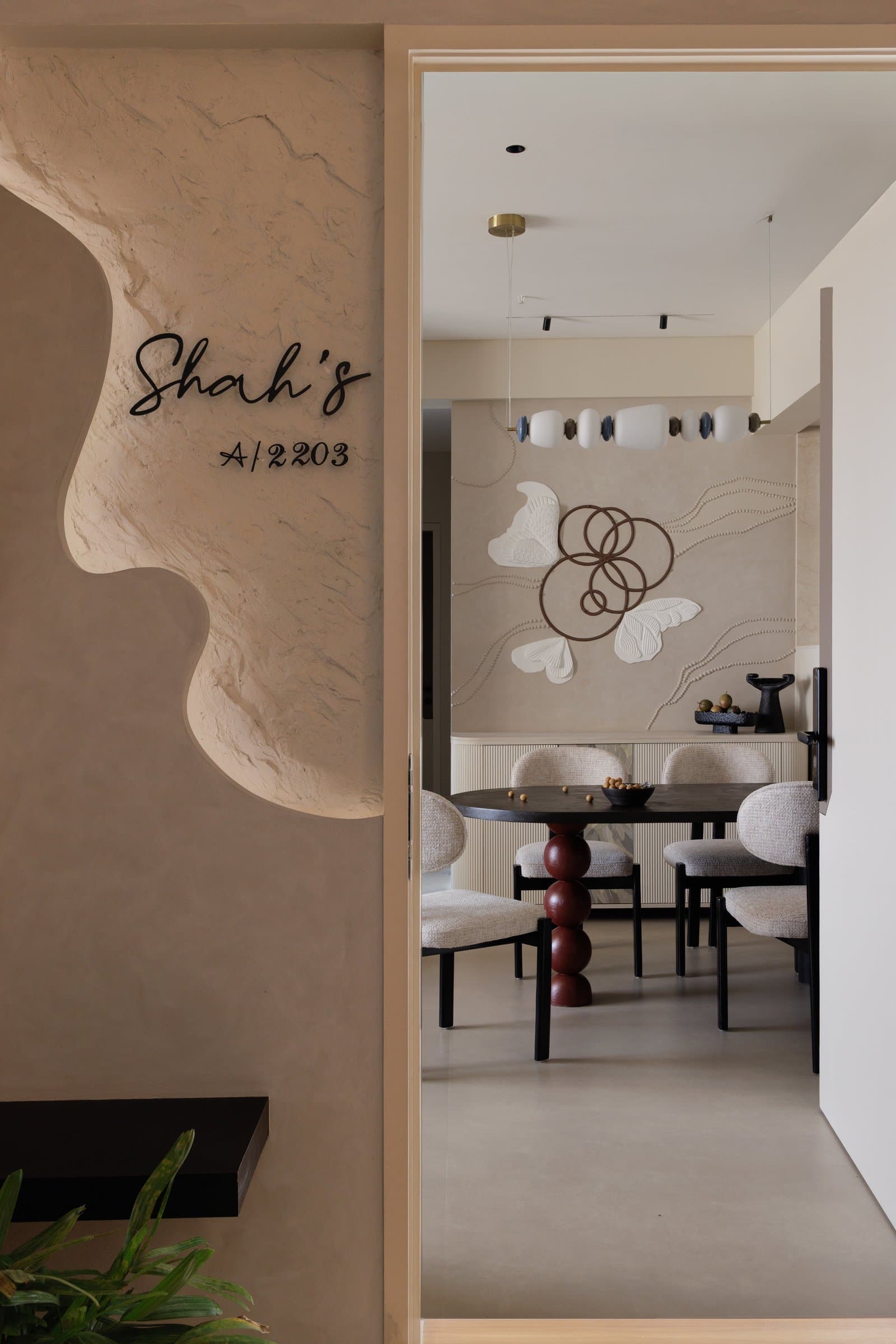 The entrance, where a sculpted plaster niche carrying the family's name frames a first glimpse of the dining room beyond