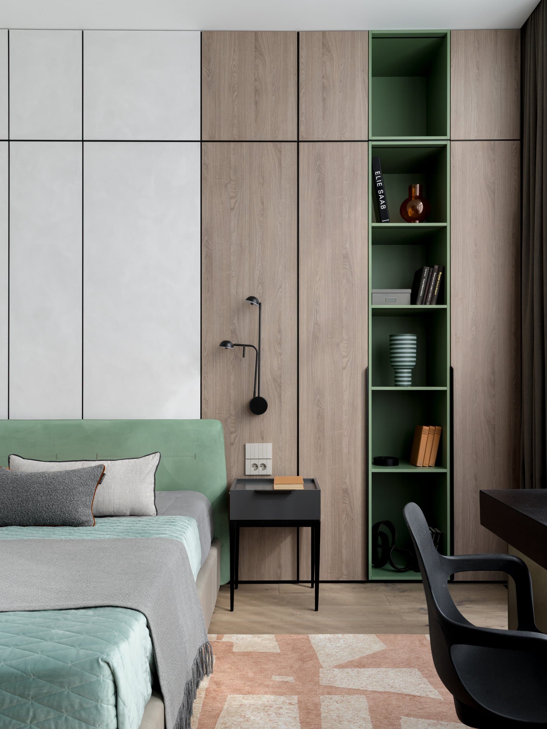 The children's room, where soft green accents thread through pale oak joinery and an upholstered headboard wall