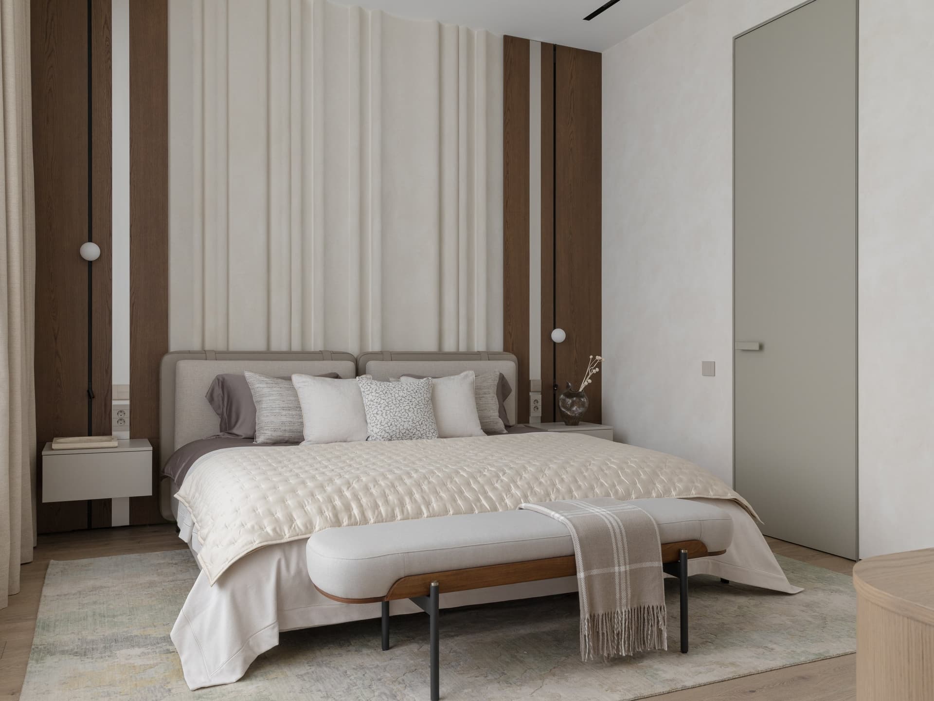 The master bedroom, where a channelled upholstered headboard wall is framed by slim bands of dark oak