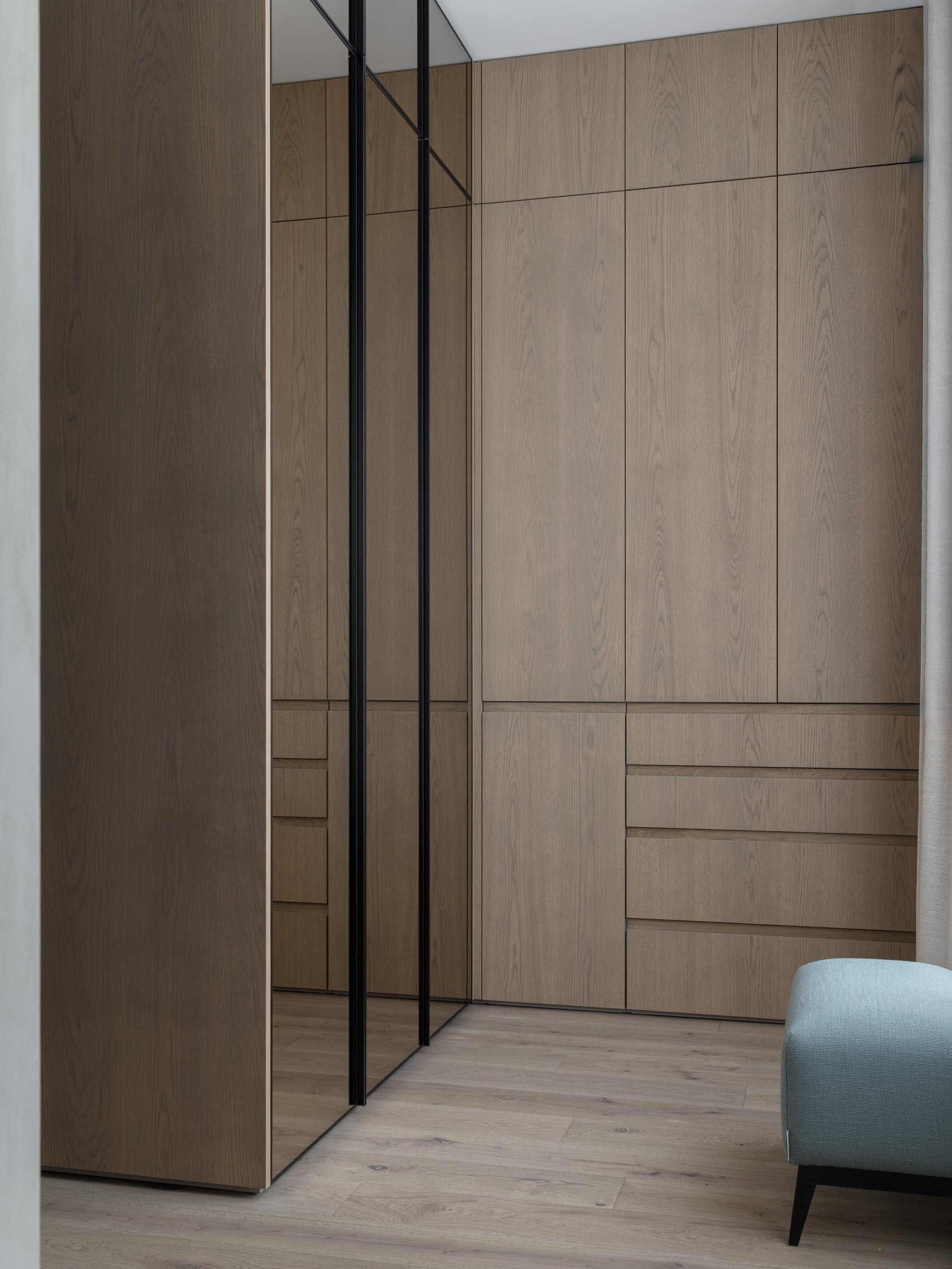 The dressing area, where full-height oak cabinetry meets a mirrored panel that lengthens the volume