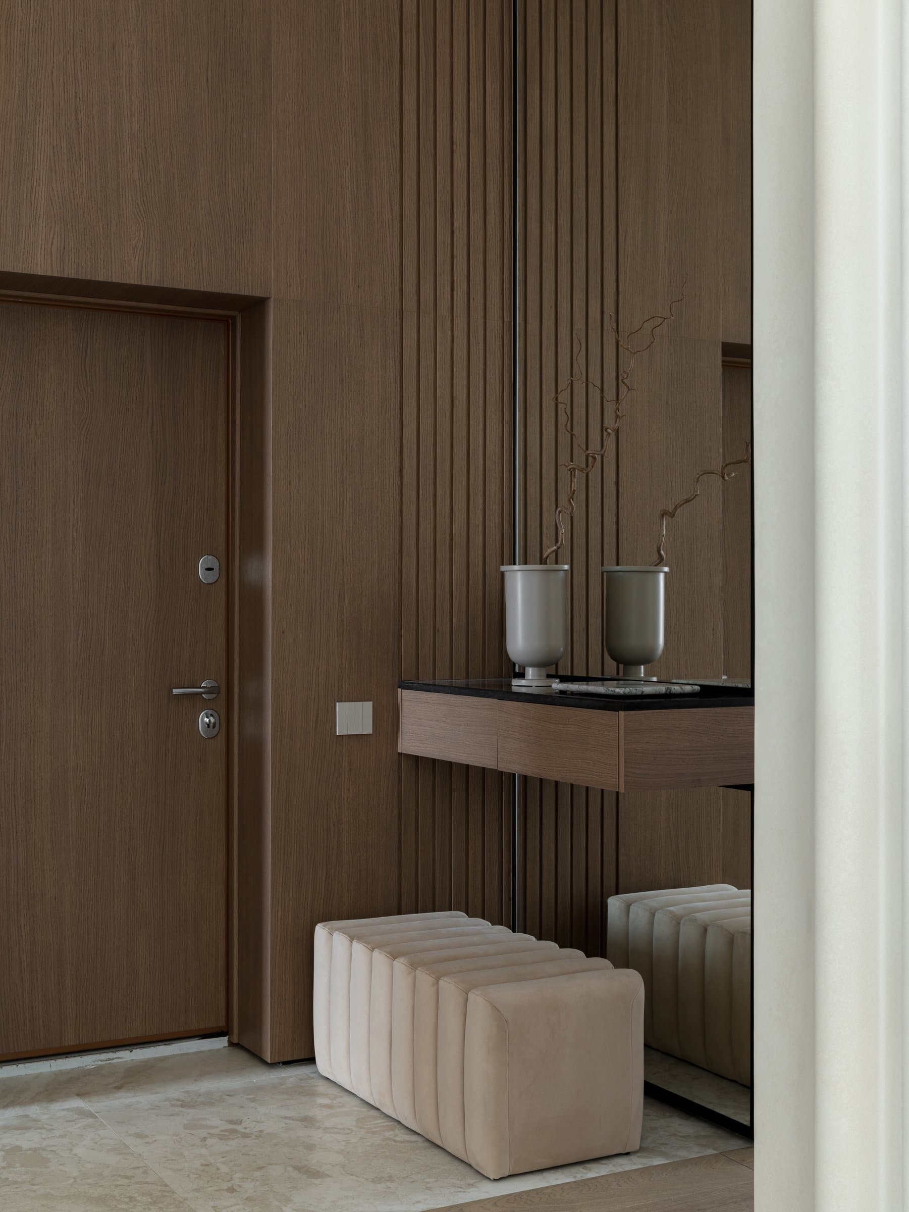The threshold, where vertical oak panelling and finely ribbed joinery establish the home's warm material register