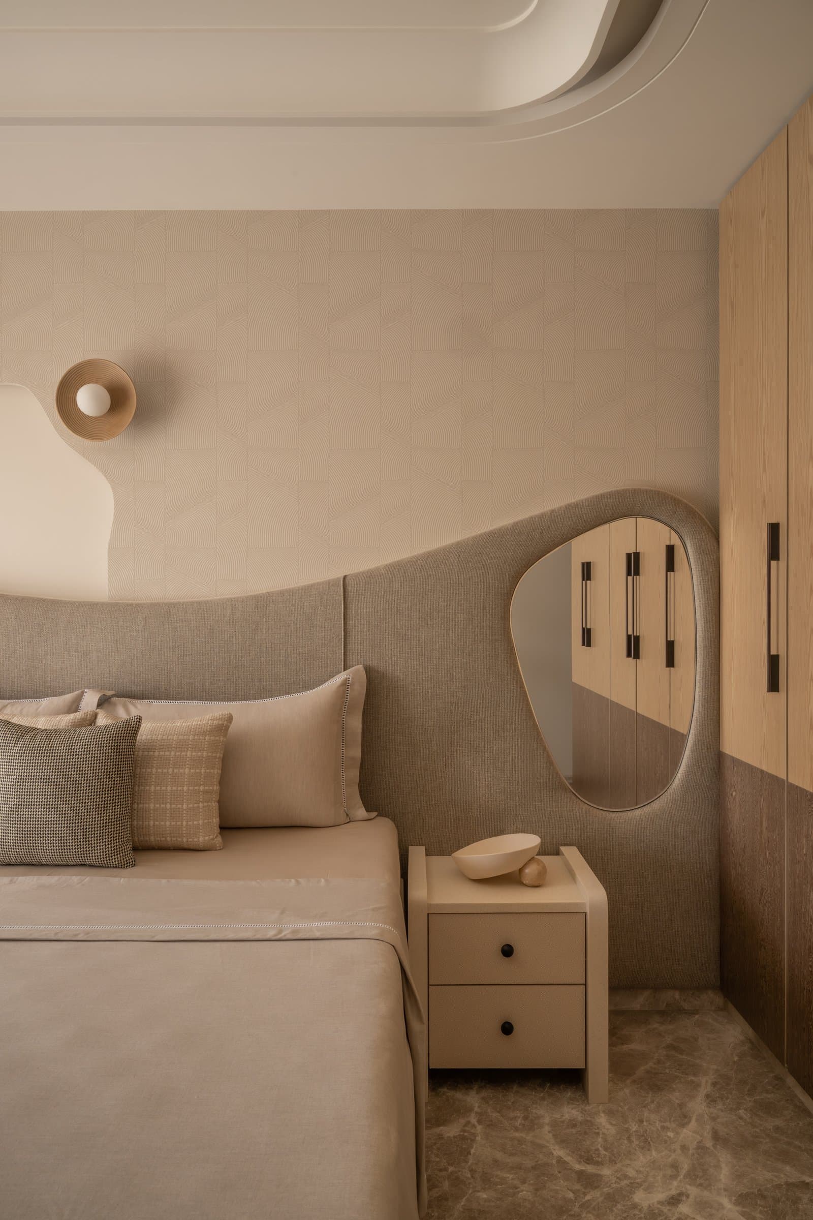 The master bedroom, viewed toward the wardrobe wall where a shaped mirror softens the timber joinery