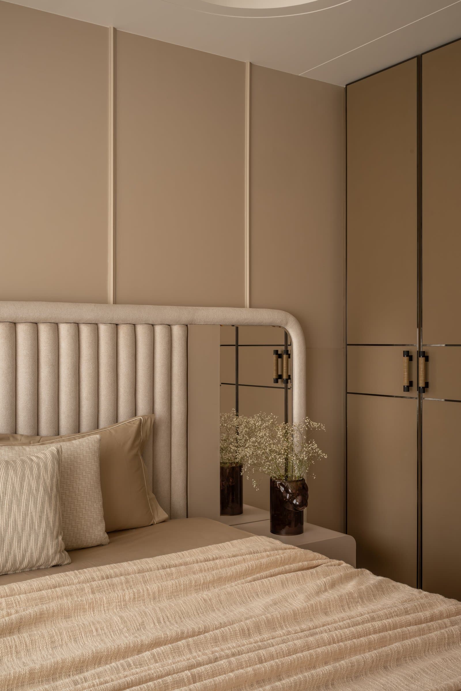 The guest bedroom, viewed toward the wardrobe wall where panelled millwork meets a fluted upholstered headboard