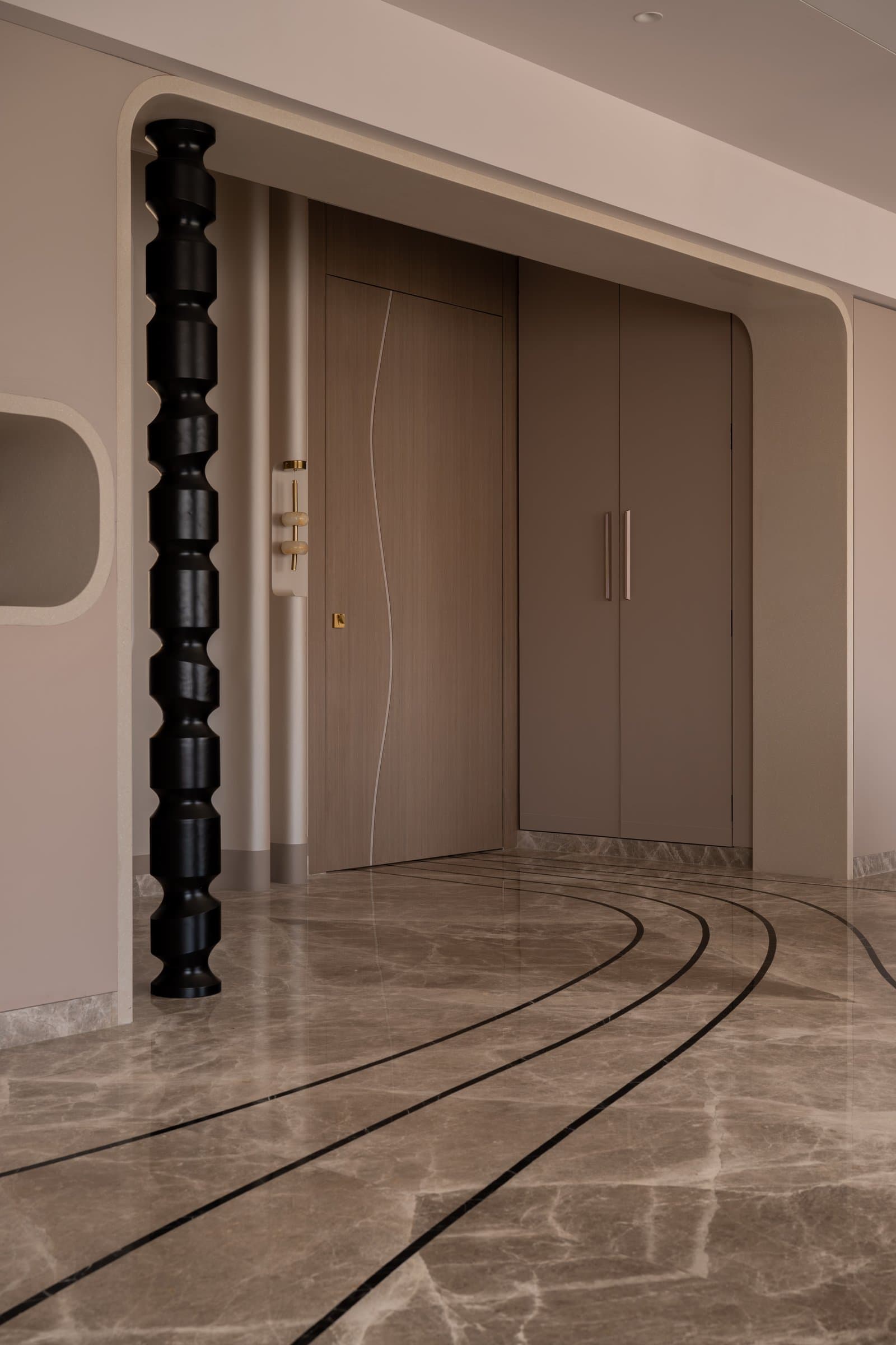 The foyer, where a turned black column and softly arched threshold set the sculptural vocabulary of the home