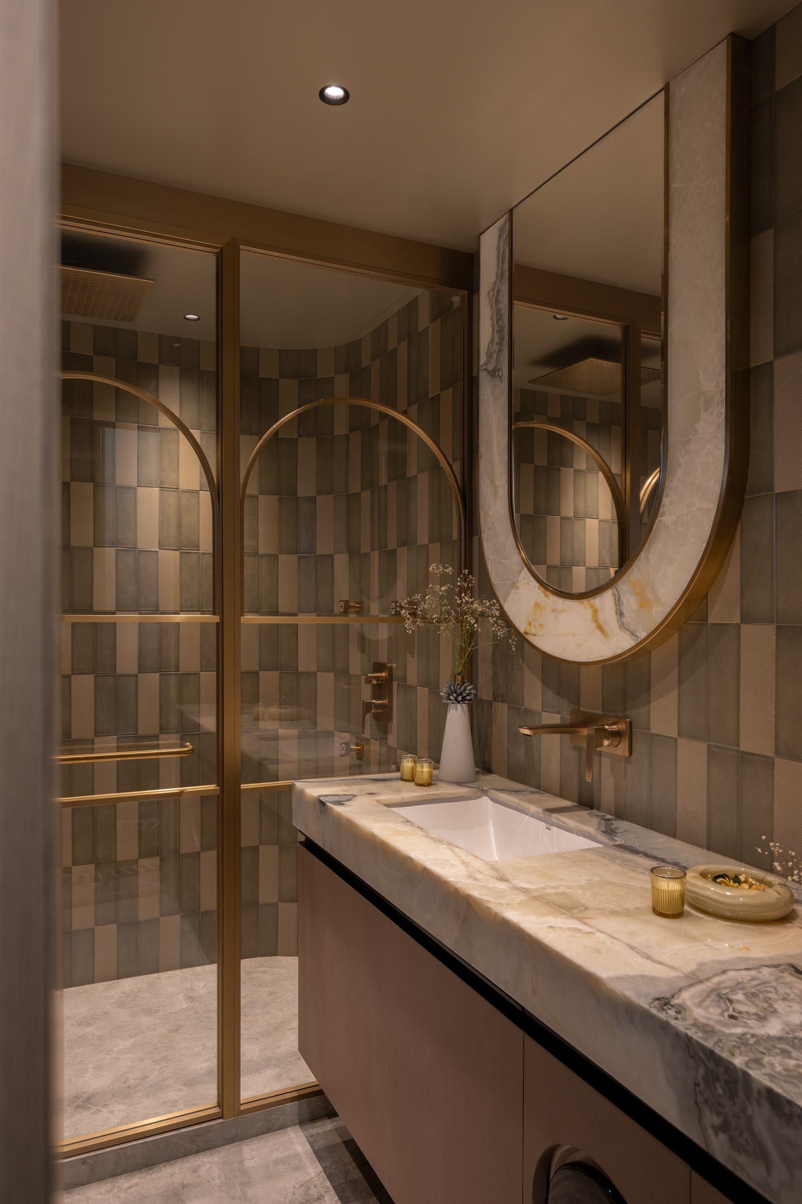 The guest bath, where checkerboard tiling in muted greys meets a stone counter and warm metal detailing