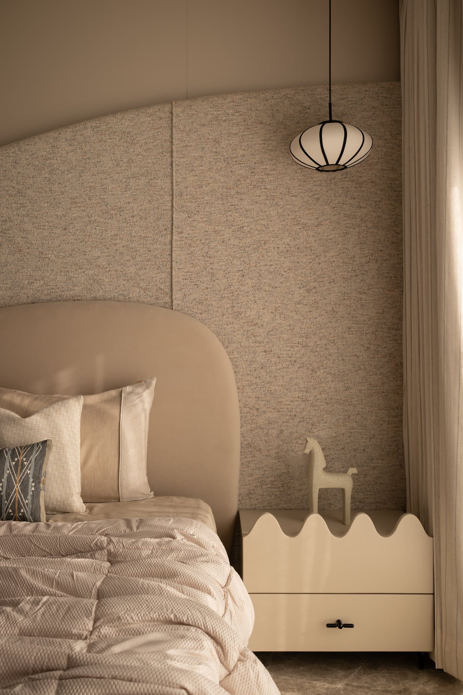 The second bedroom, seen toward a curved bedside cabinet whose scalloped edge softens the corner