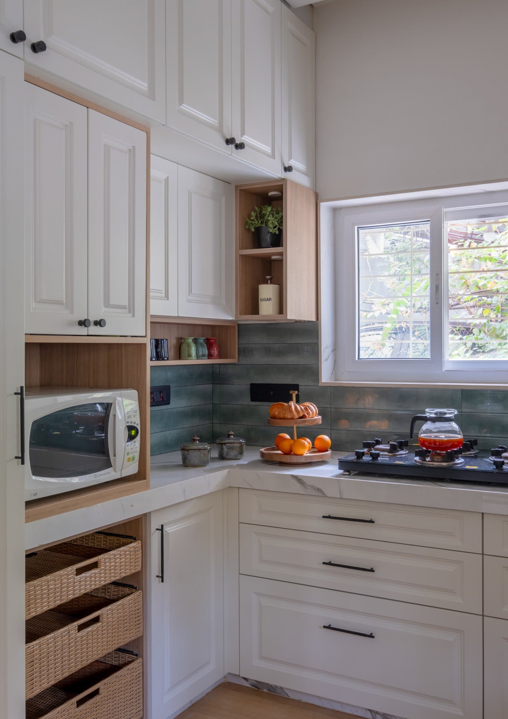 A closer view of the kitchen's storage, with woven baskets and warm wooden niches interrupting the cream run