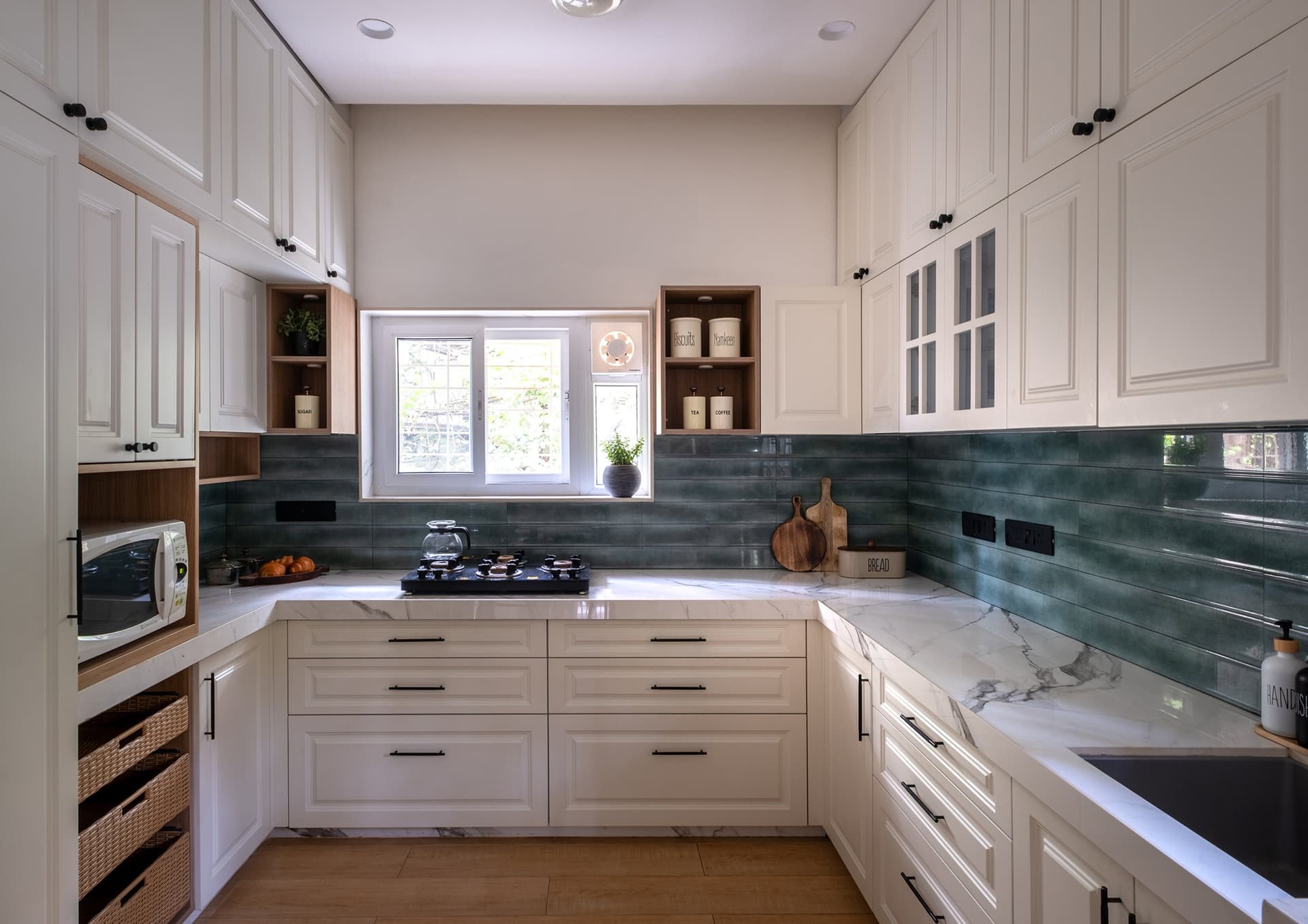 The kitchen, where cream farmhouse cabinetry meets a green tiled backsplash and a stone-look counter