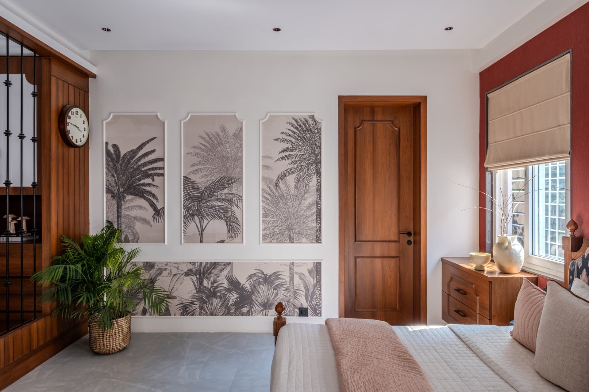 The master bedroom, where framed tropical wallpaper panels sit against a deep red accent wall
