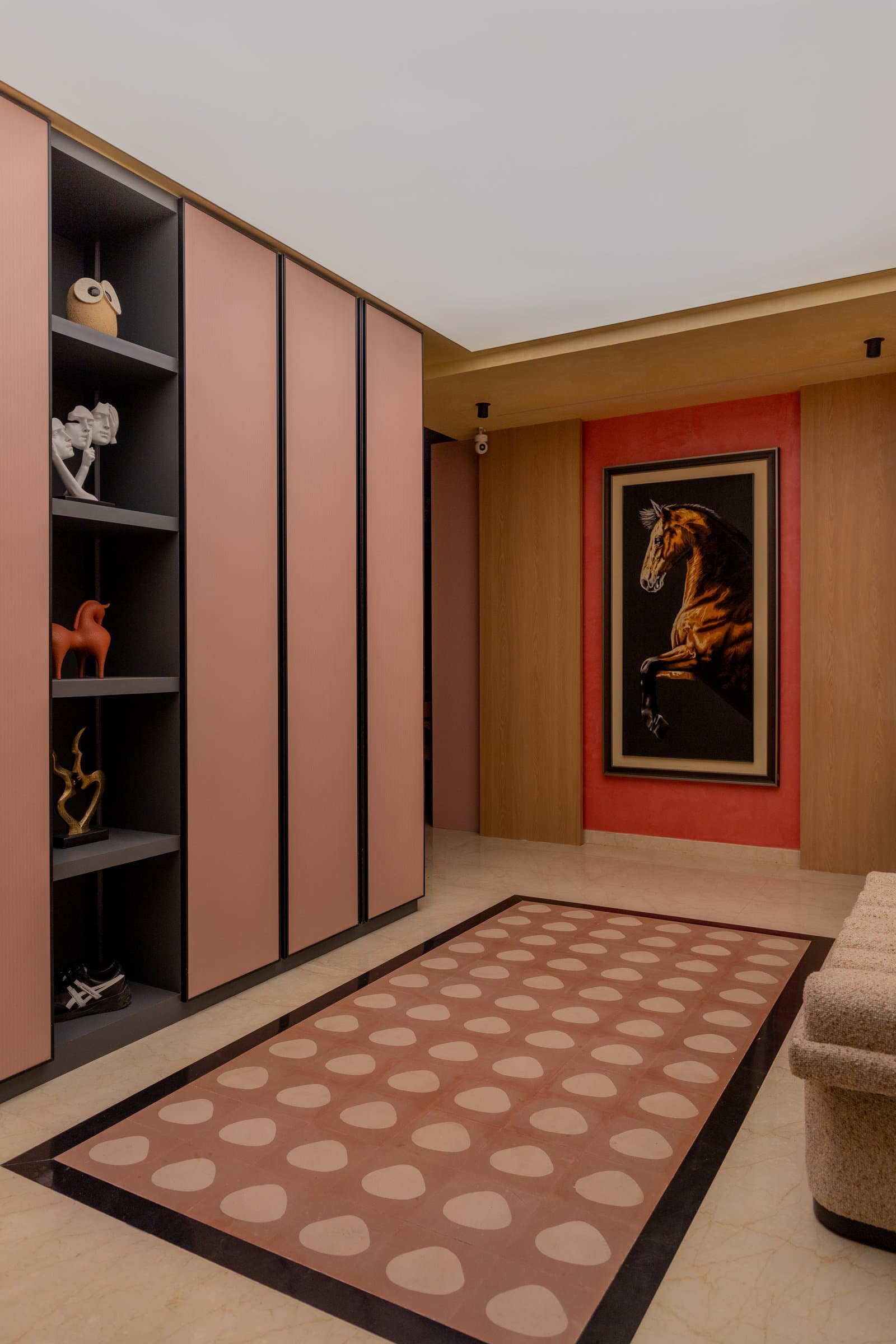 The foyer, where a dusty-pink storage wall and a terracotta-grounded equestrian artwork set the home's material palette