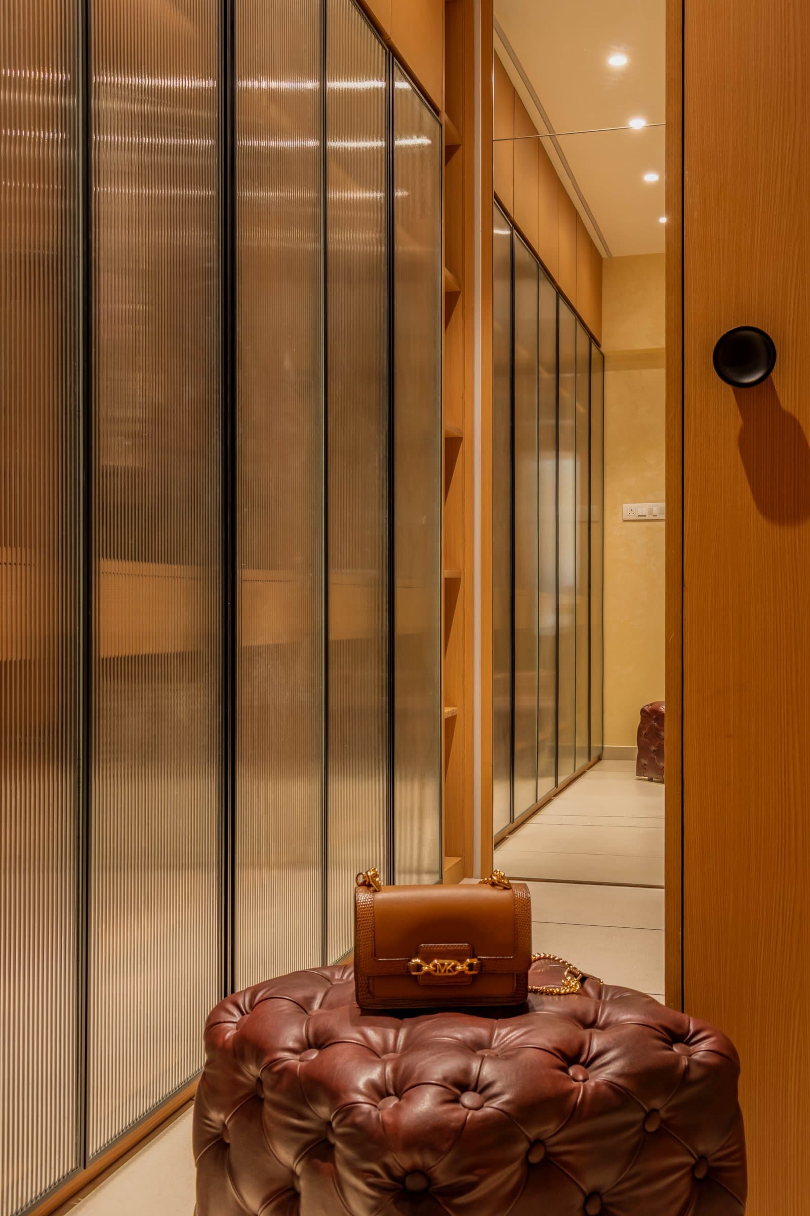 The dressing corridor, where reeded-glass wardrobe fronts filter light into a soft golden glow