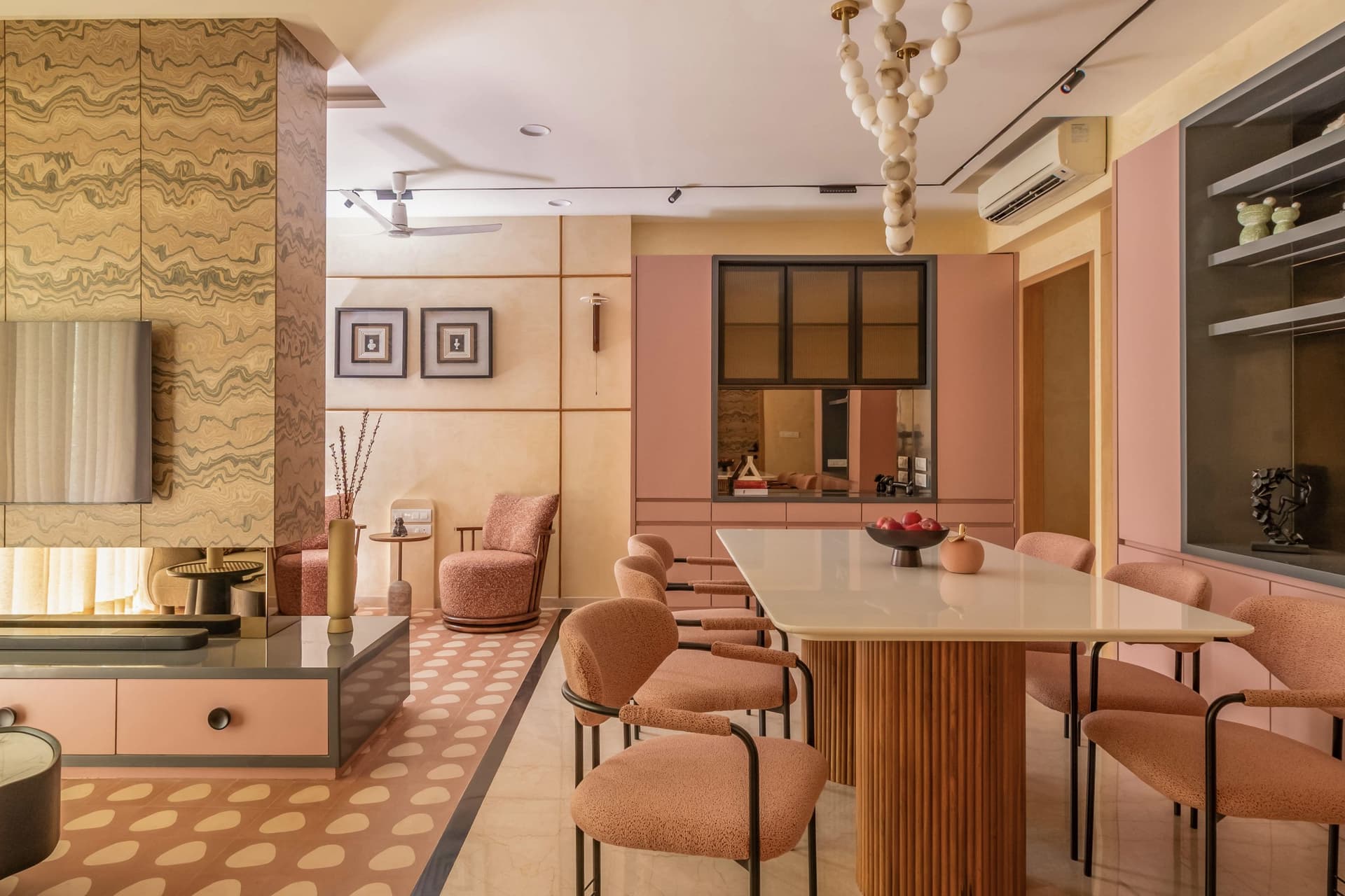 The dining area, with a fluted wooden pedestal table beneath a sculptural pendant of pale spherical modules