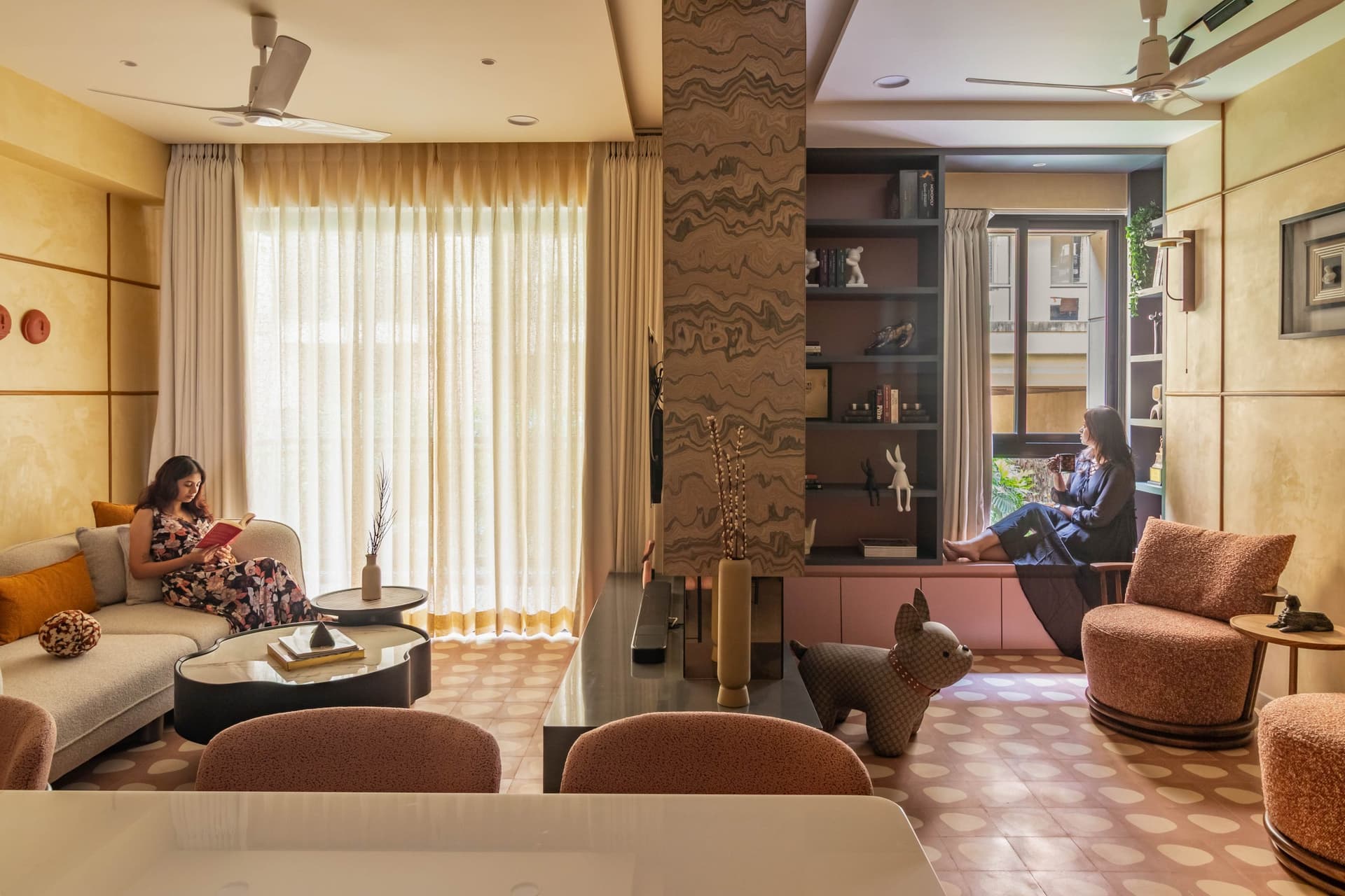 The living room, anchored by a book-matched stone column and a window-seat nook built into the far corner