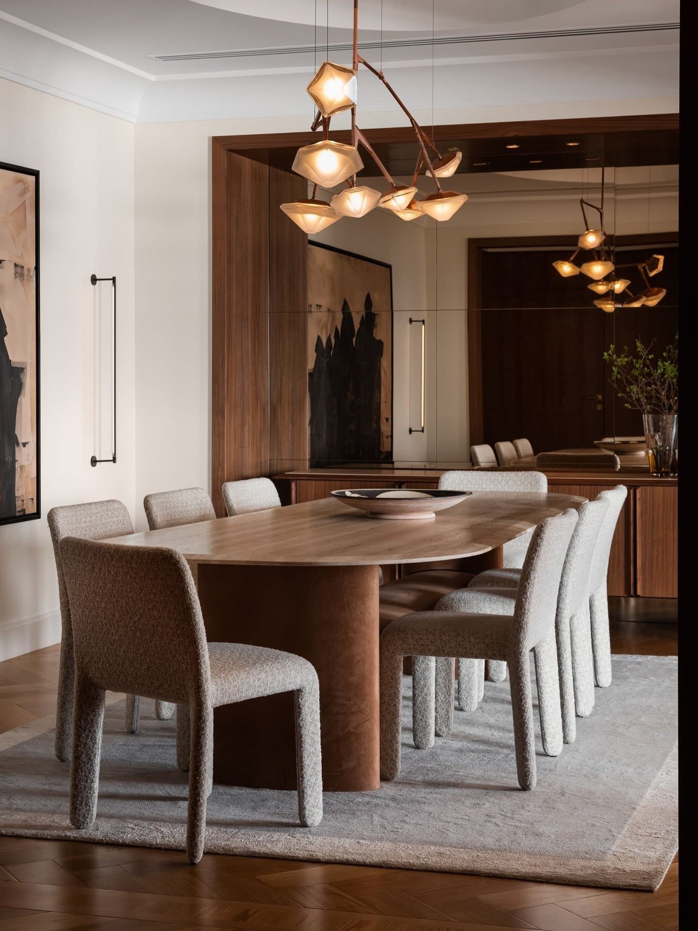 The dining room, anchored by a walnut oval table and a branching brass chandelier.