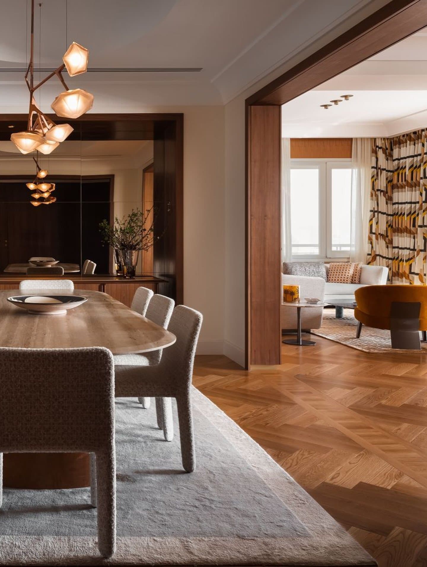 A mirrored opening threads the dining and living rooms into a single spatial sequence.