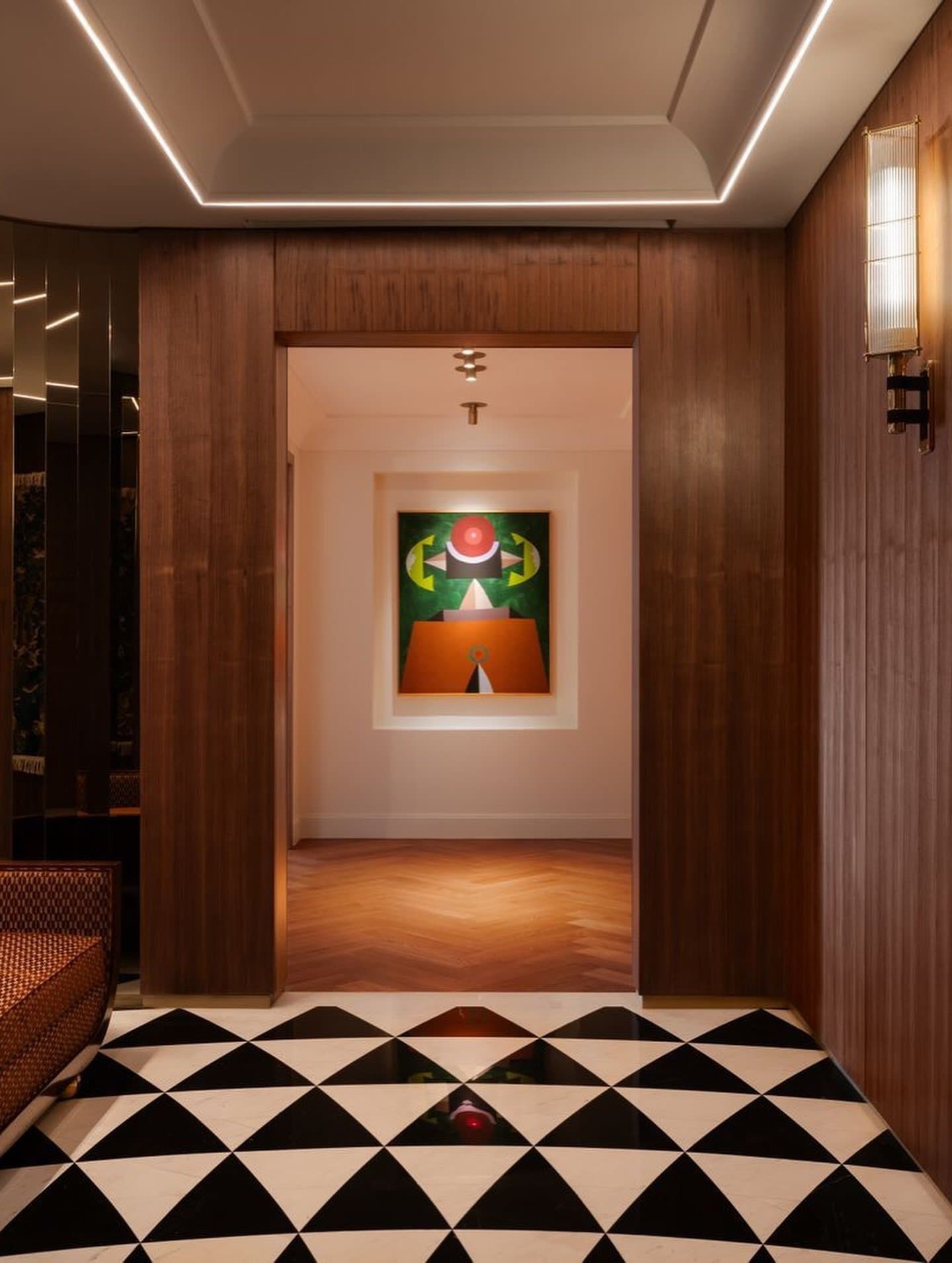 A wood-clad passage staged around a black-and-white triangular marble floor.