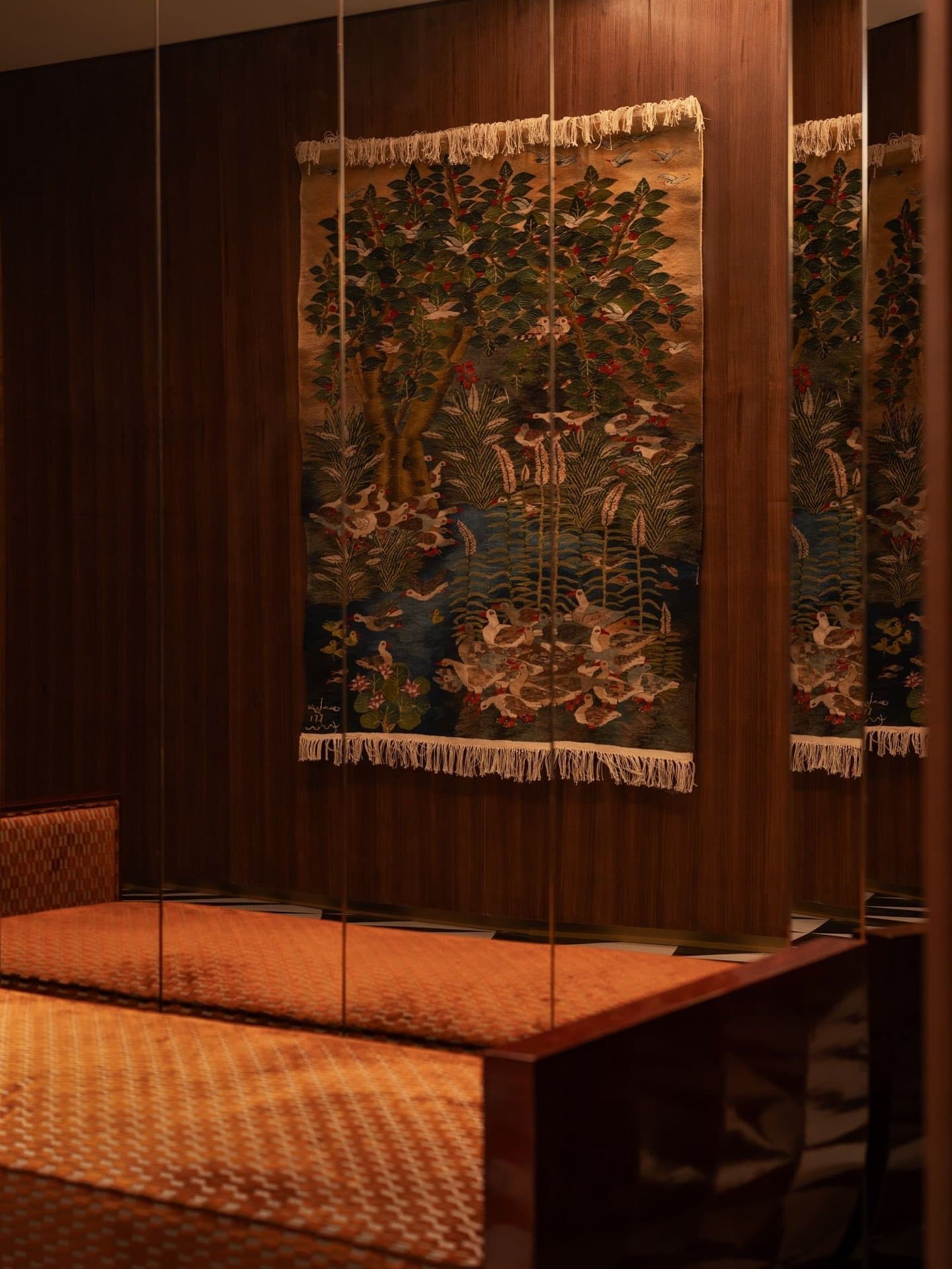 The bedroom's woven tapestry and mirrored slivers reframe Egyptian memory as material.