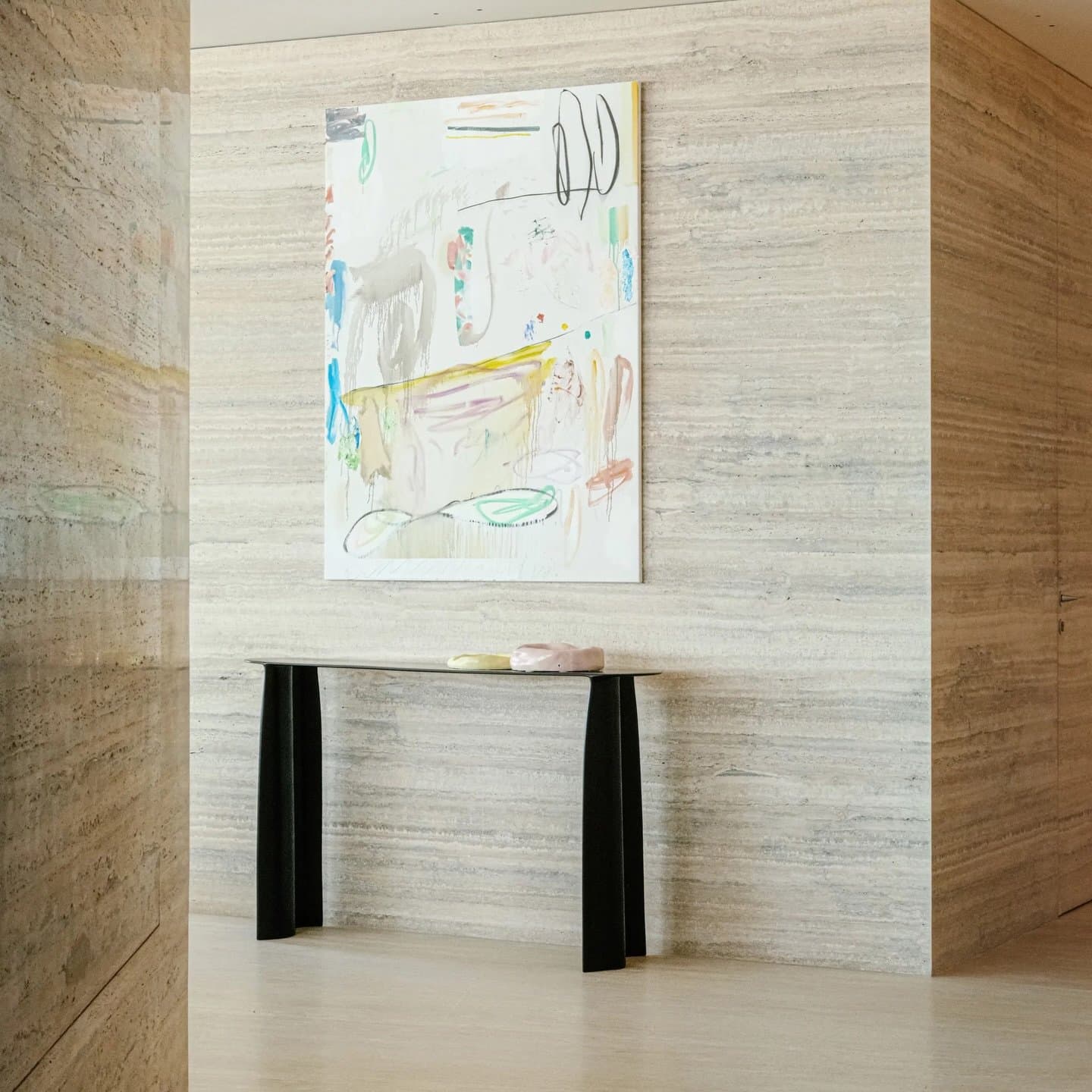 The foyer, lined in book-matched stone, offers a restrained threshold marked by a single abstract painting.