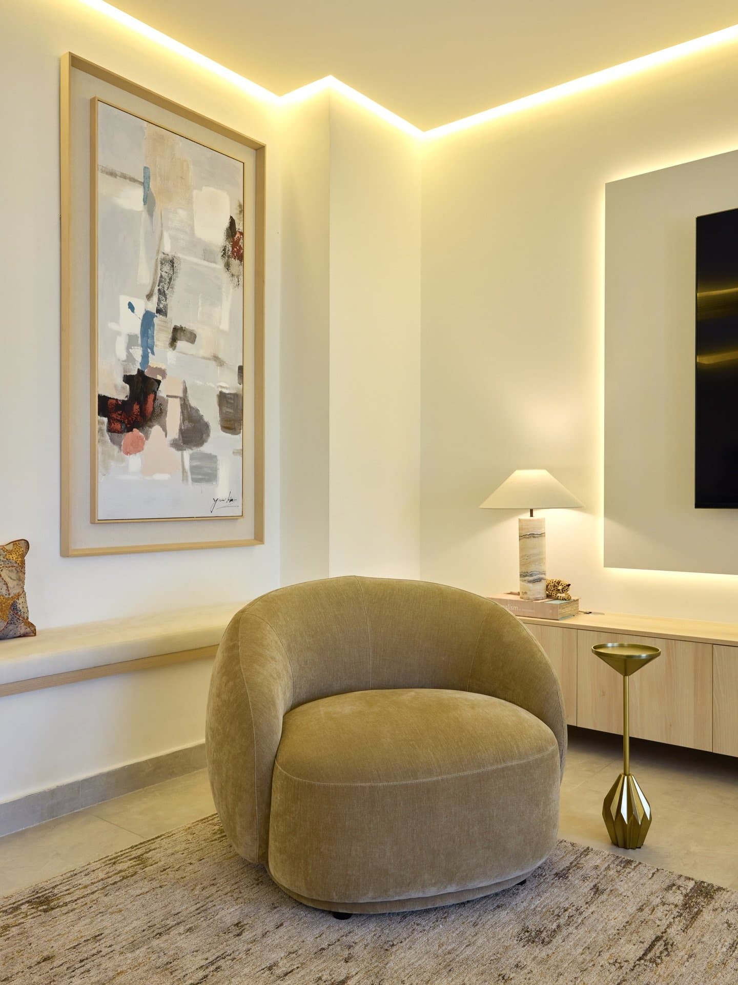 A quiet corner of the primary suite, where an olive velvet armchair rests against a muted composition.