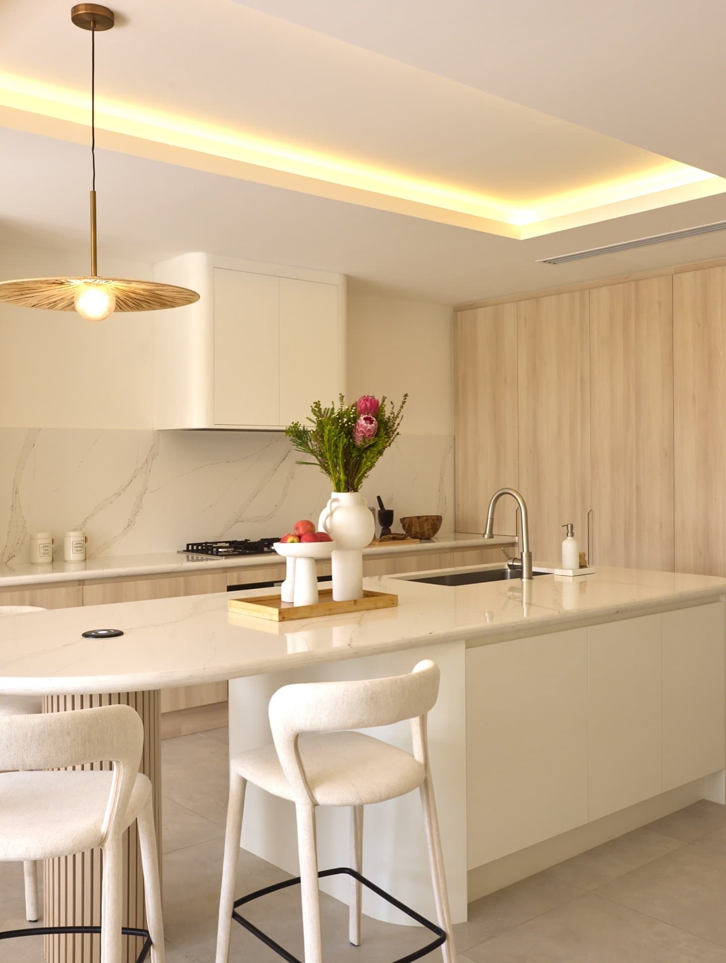 A waterfall-edge island and boucle-upholstered stools introduce a moment of intimacy.