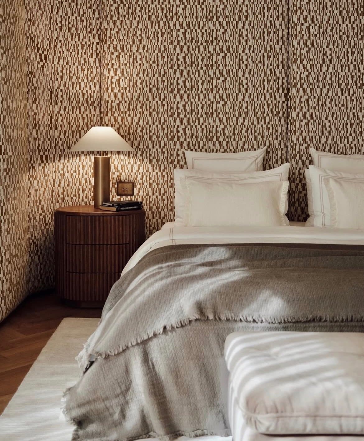 A fluted nightstand and upholstered wall bring the same restraint into the private quarters.
