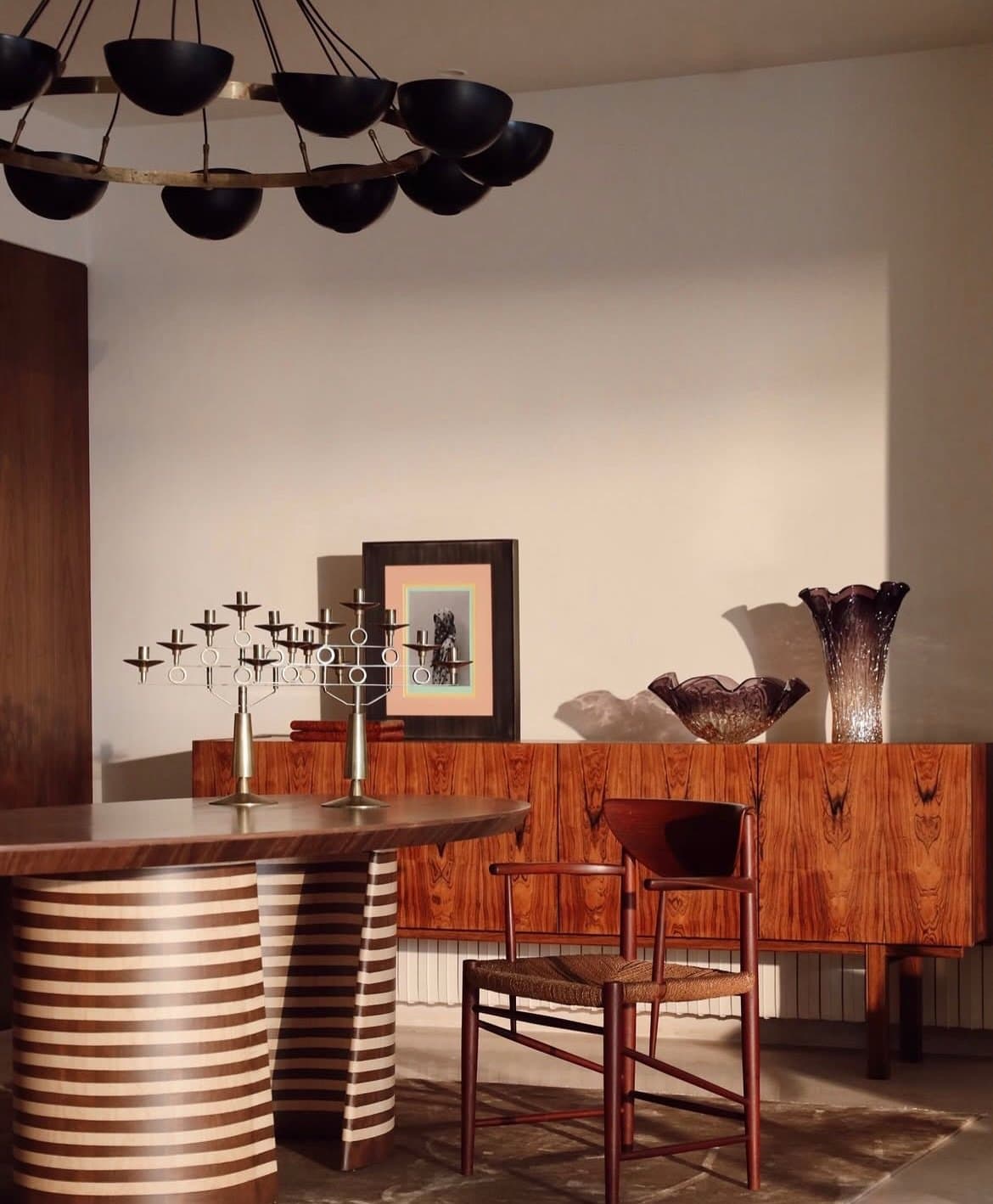 A blackened-dome chandelier above a book-matched sideboard in the dining corner.