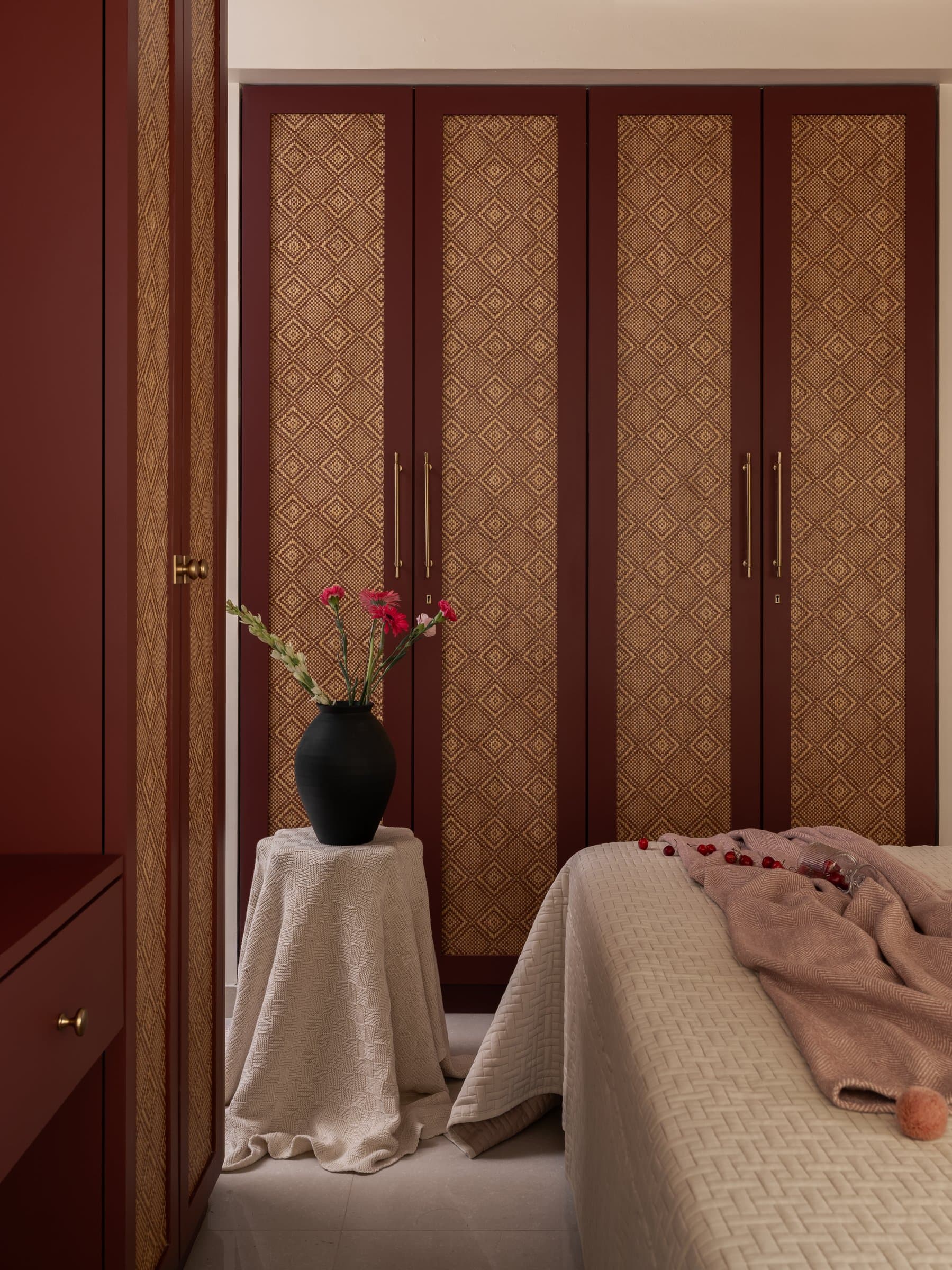 The master wardrobe, its deep oxblood fronts inset with diamond-patterned woven cane
