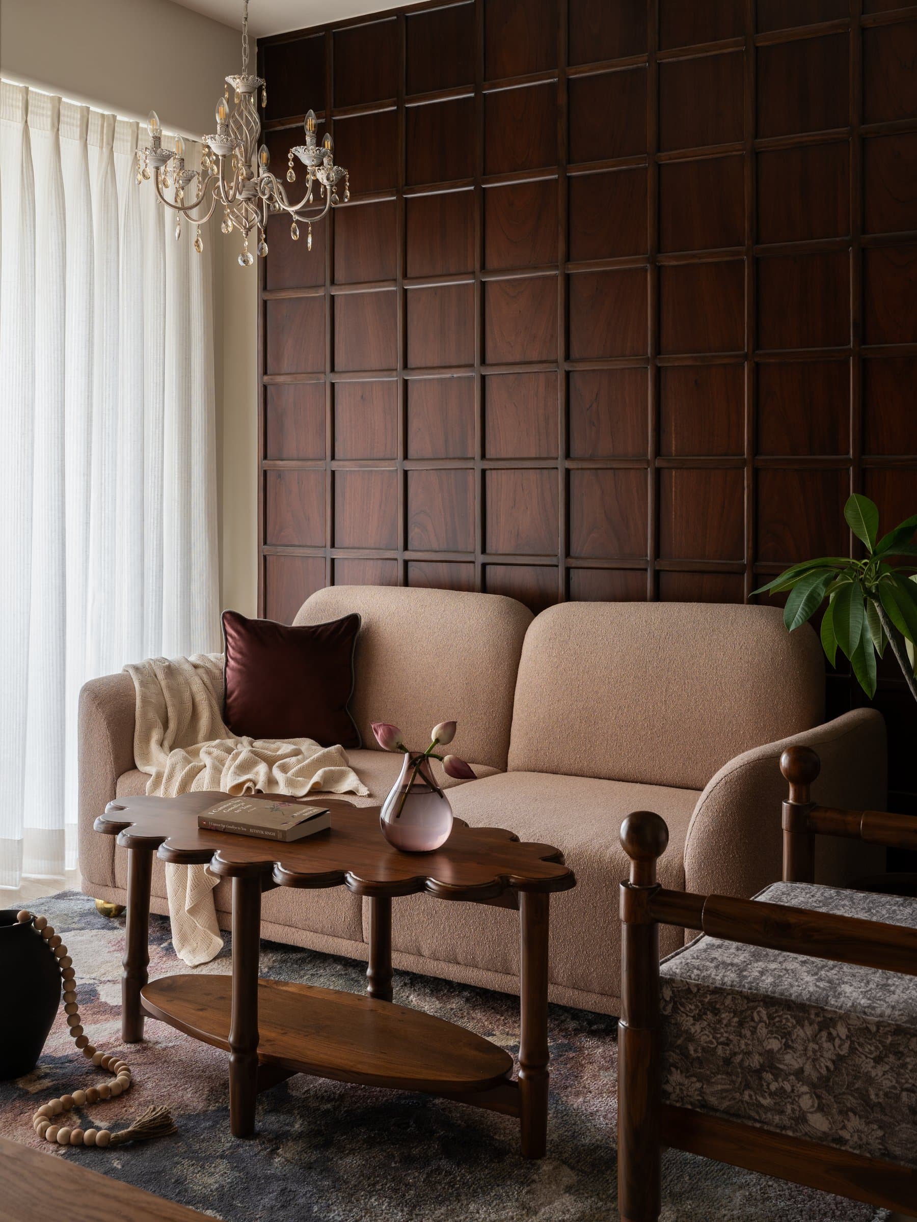 The living room, where a curved bouclé sofa softens the disciplined grid of the teak feature wall behind it