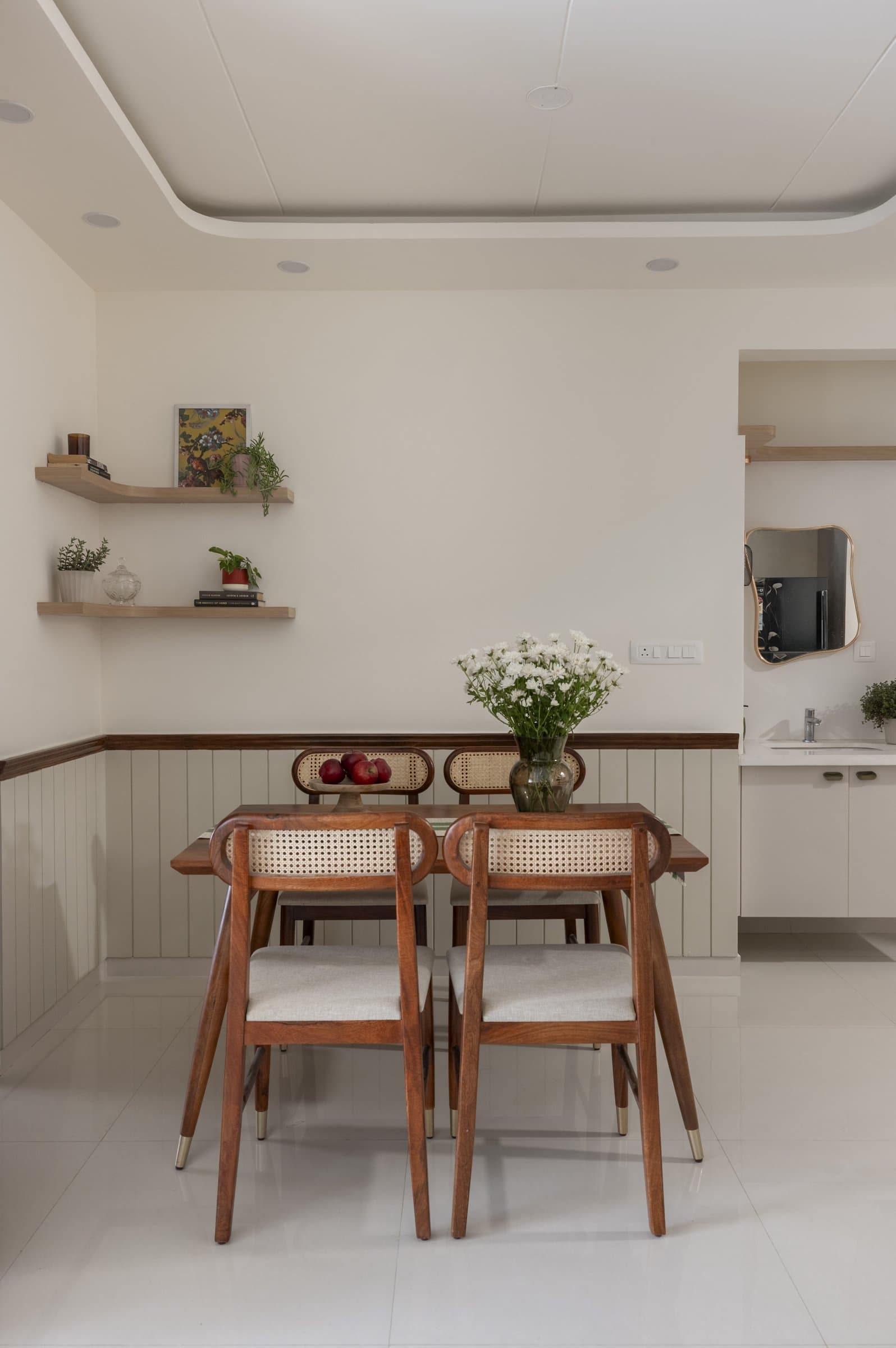 The dining area, where cane-back chairs and a pair of floating shelves quietly close the composition