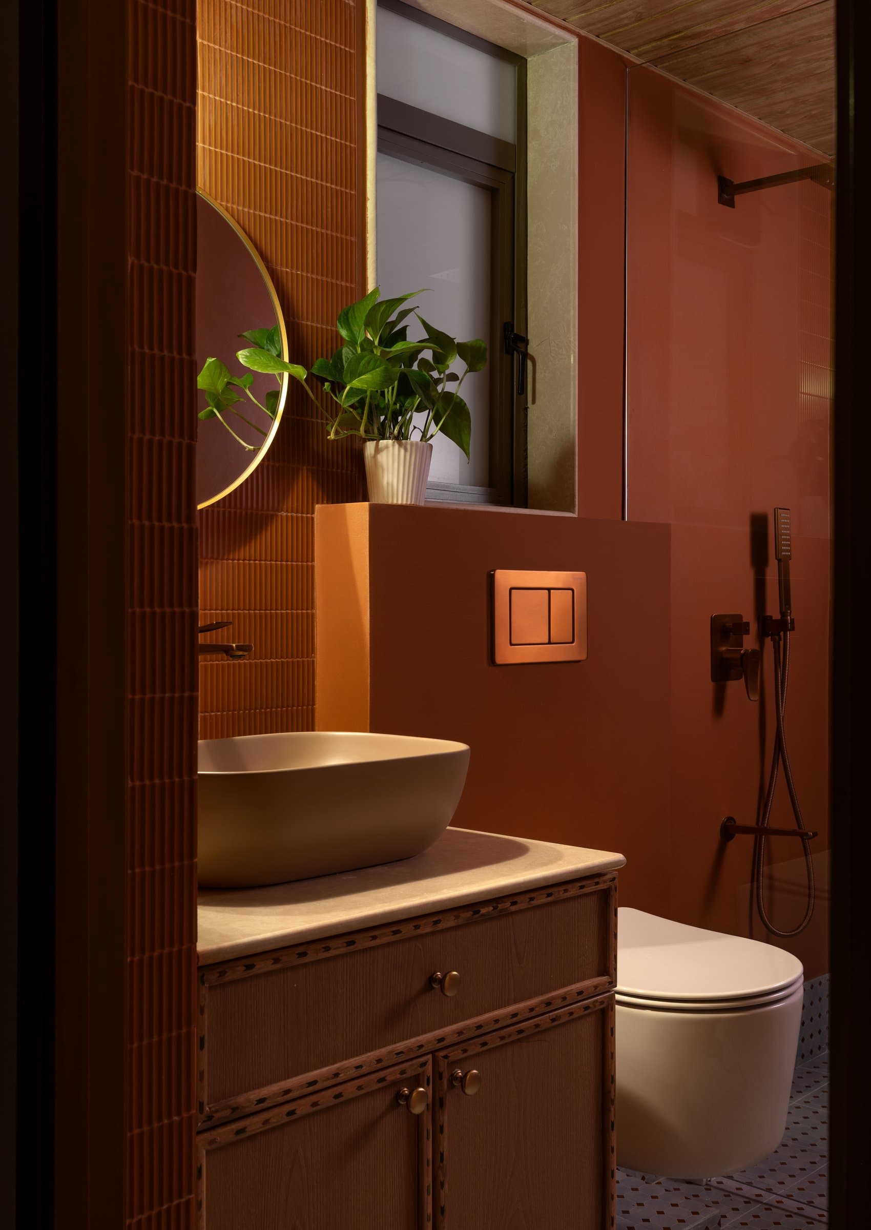 The primary bathroom, where terracotta tiles and a soft ochre basin commit fully to the home's warmest register
