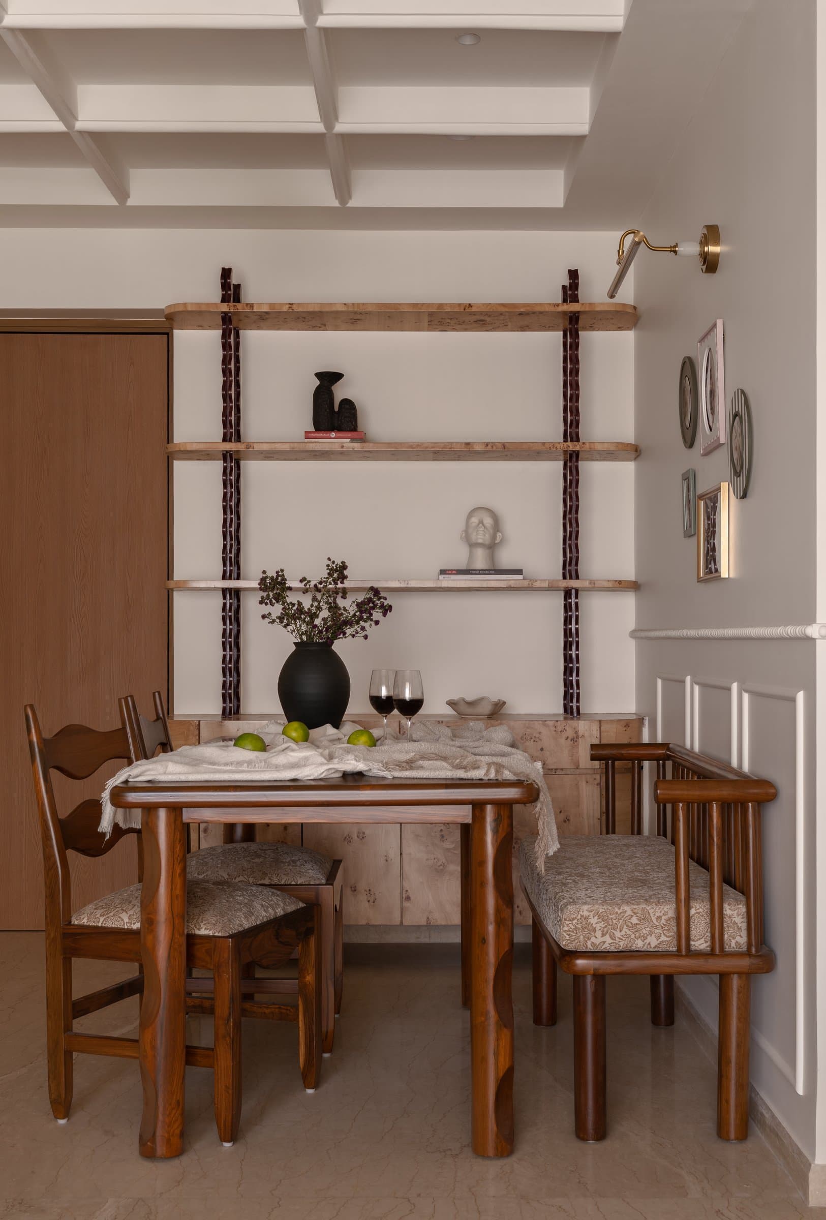 The dining area, where a spindle-backed bench and burl-wood shelving suspended on leather straps compose a quietly curatorial moment
