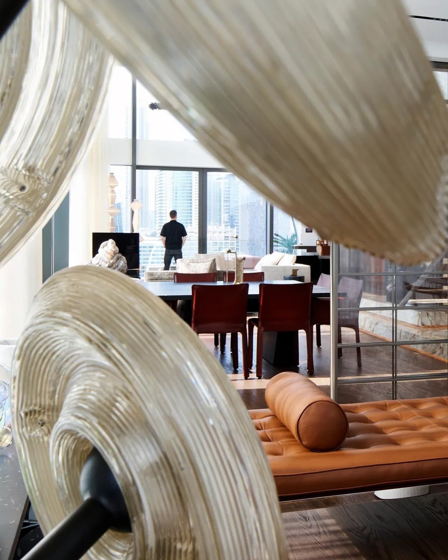 A sculptural ribbed glass lamp frames the dining and living zones, with the Dubai skyline beyond.