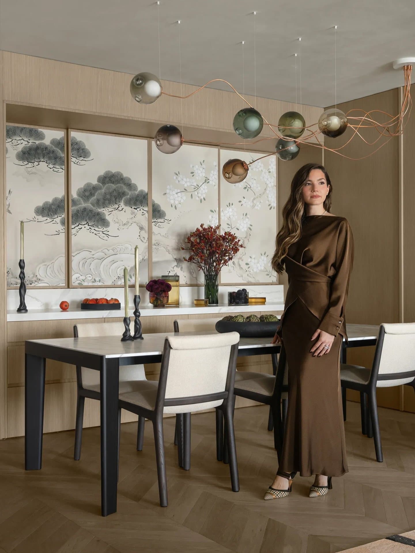 Chevron flooring and a sculptural pendant of glass spheres on copper stems compose the dining room's quiet choreography.