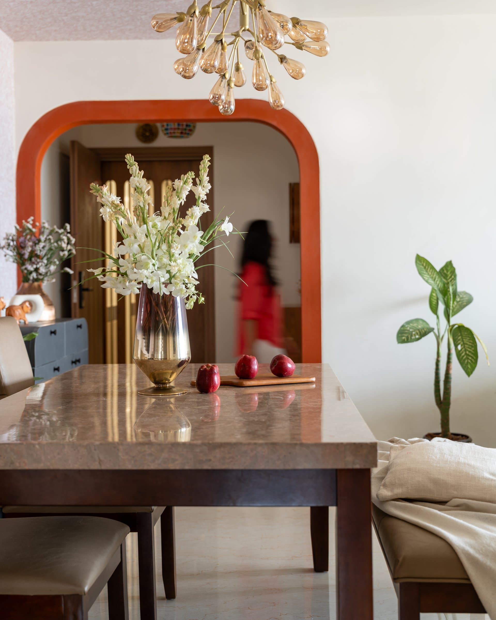 A tighter view of the dining table's warm stone top, framed again by the terracotta arch and a glimpse of the entry