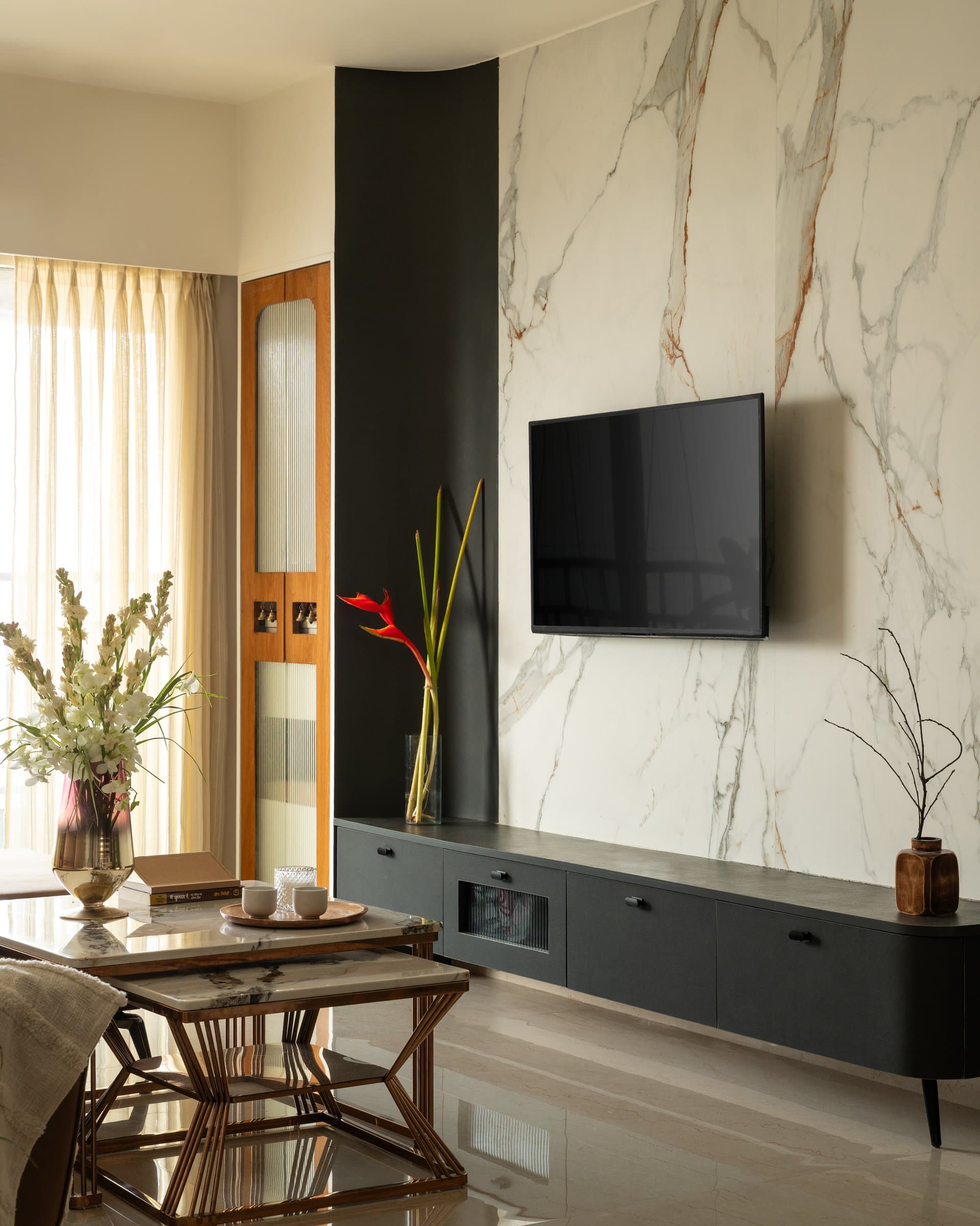 The media wall, where a veined marble panel meets a matte dark volume carrying low storage