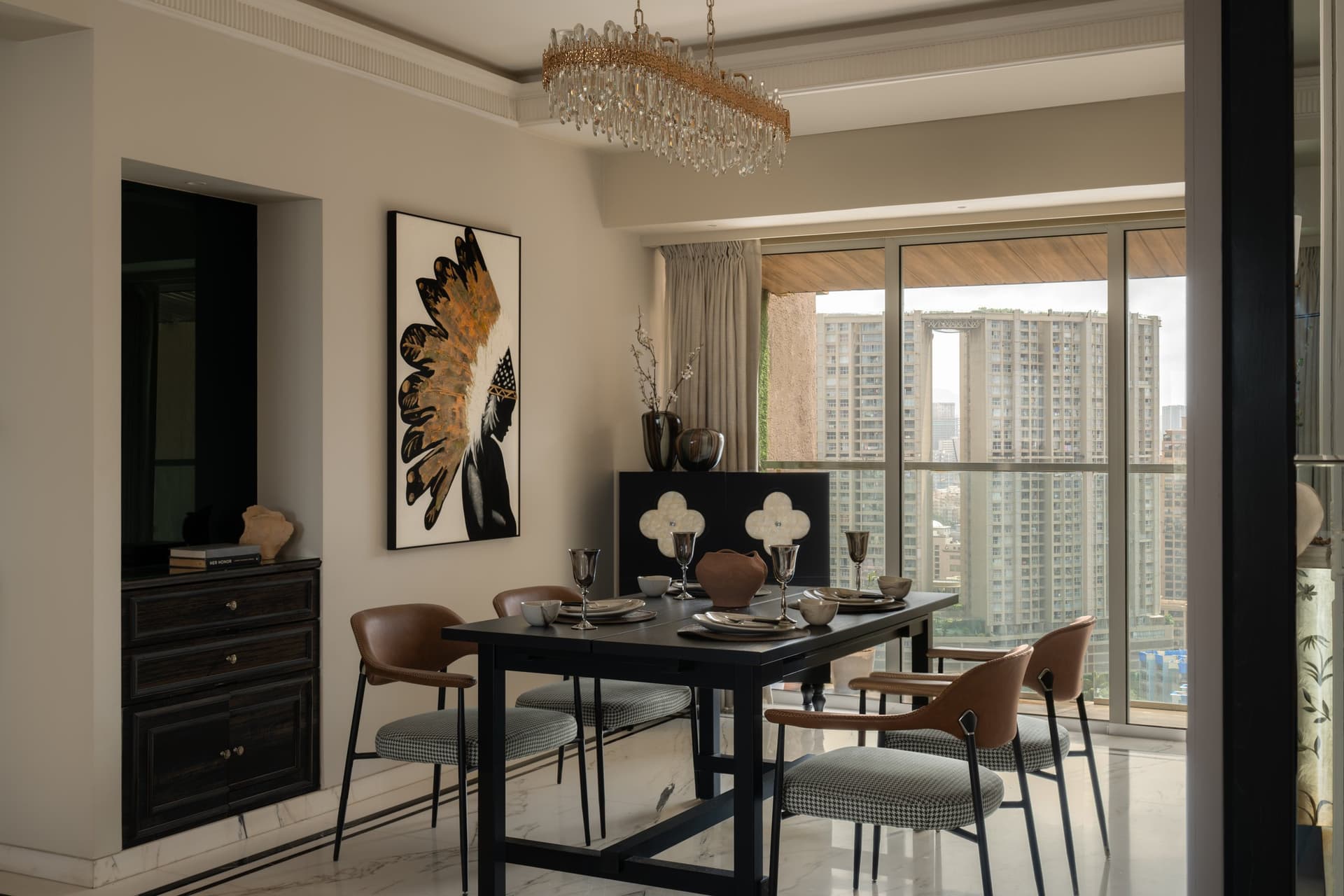 The dining area, oriented toward the Andheri skyline, held between a linear crystal chandelier and a graphic canvas