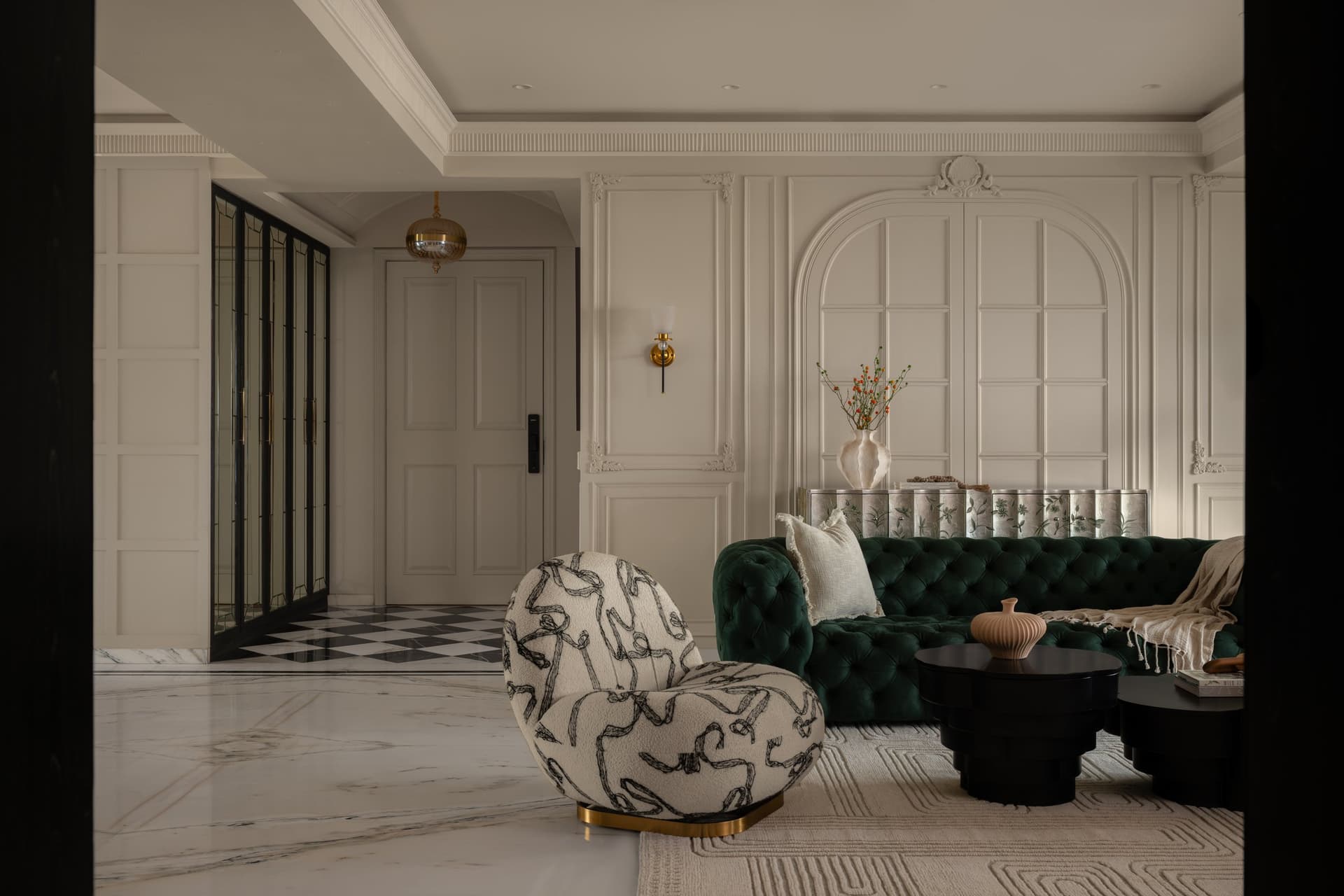 In the living room, a tufted green sofa sits beneath a plaster-arched panel with a carved cartouche