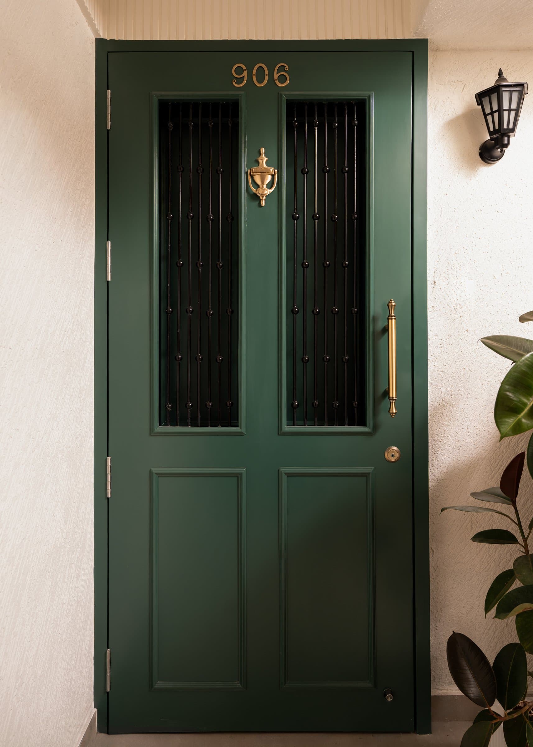 The entry door in deep green, with brass numerals and a traditional knocker, establishing the home's European register before the interior is glimpsed